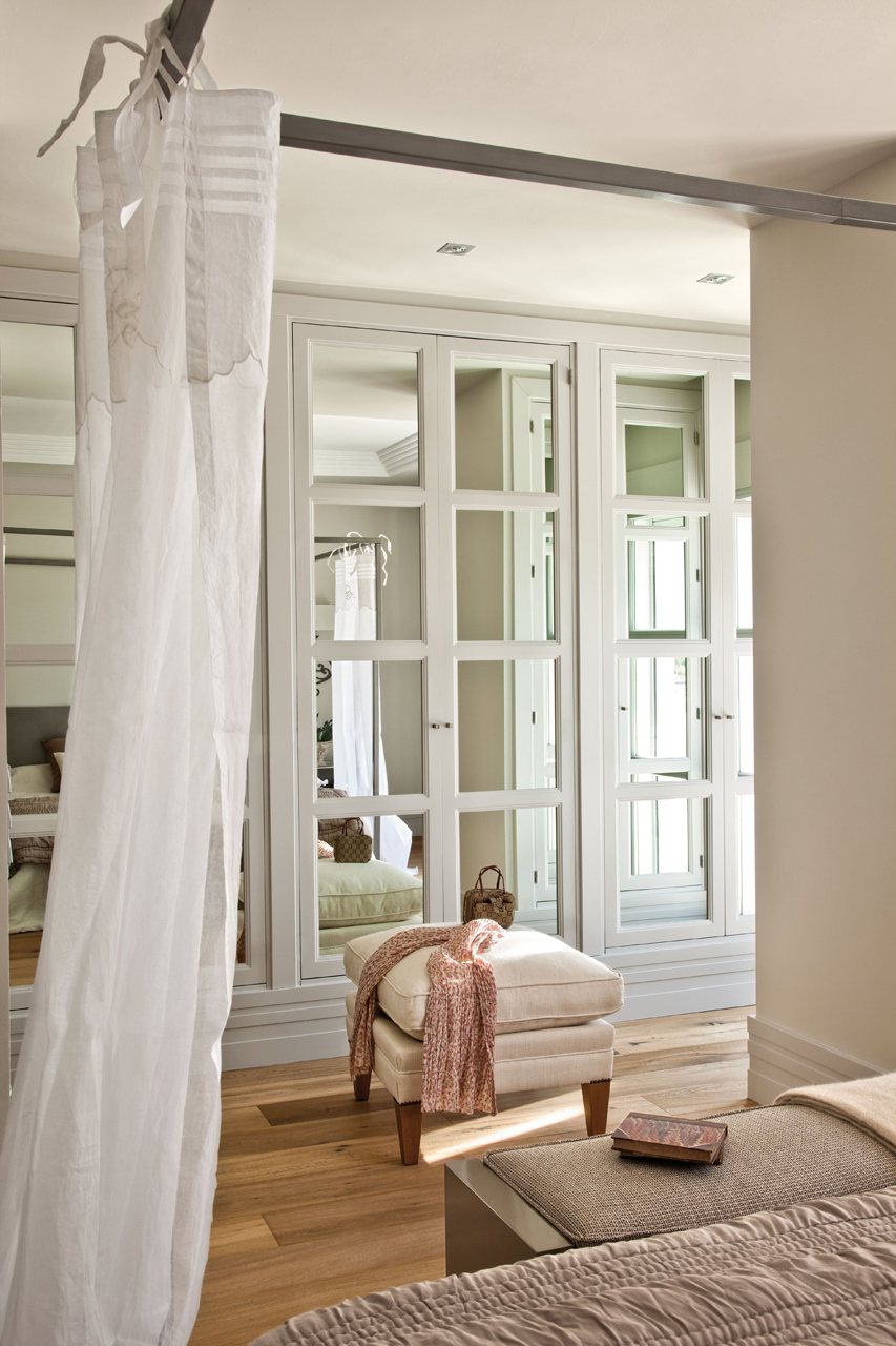 Dormitorio con vestidor con armarios lacados y frentes de espejo