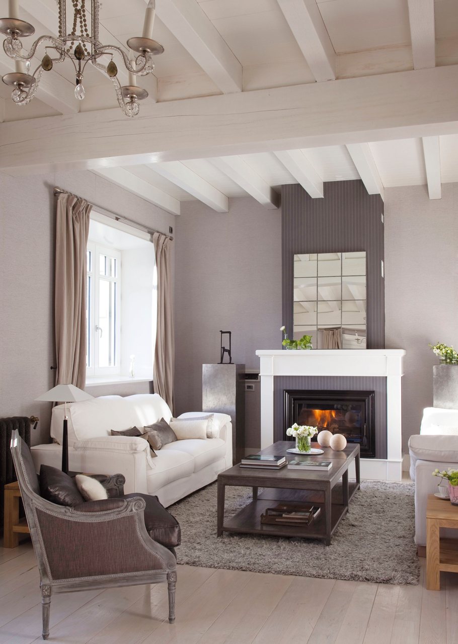 Salón de estilo clásico con chimenea decorado en blancos y grises.
