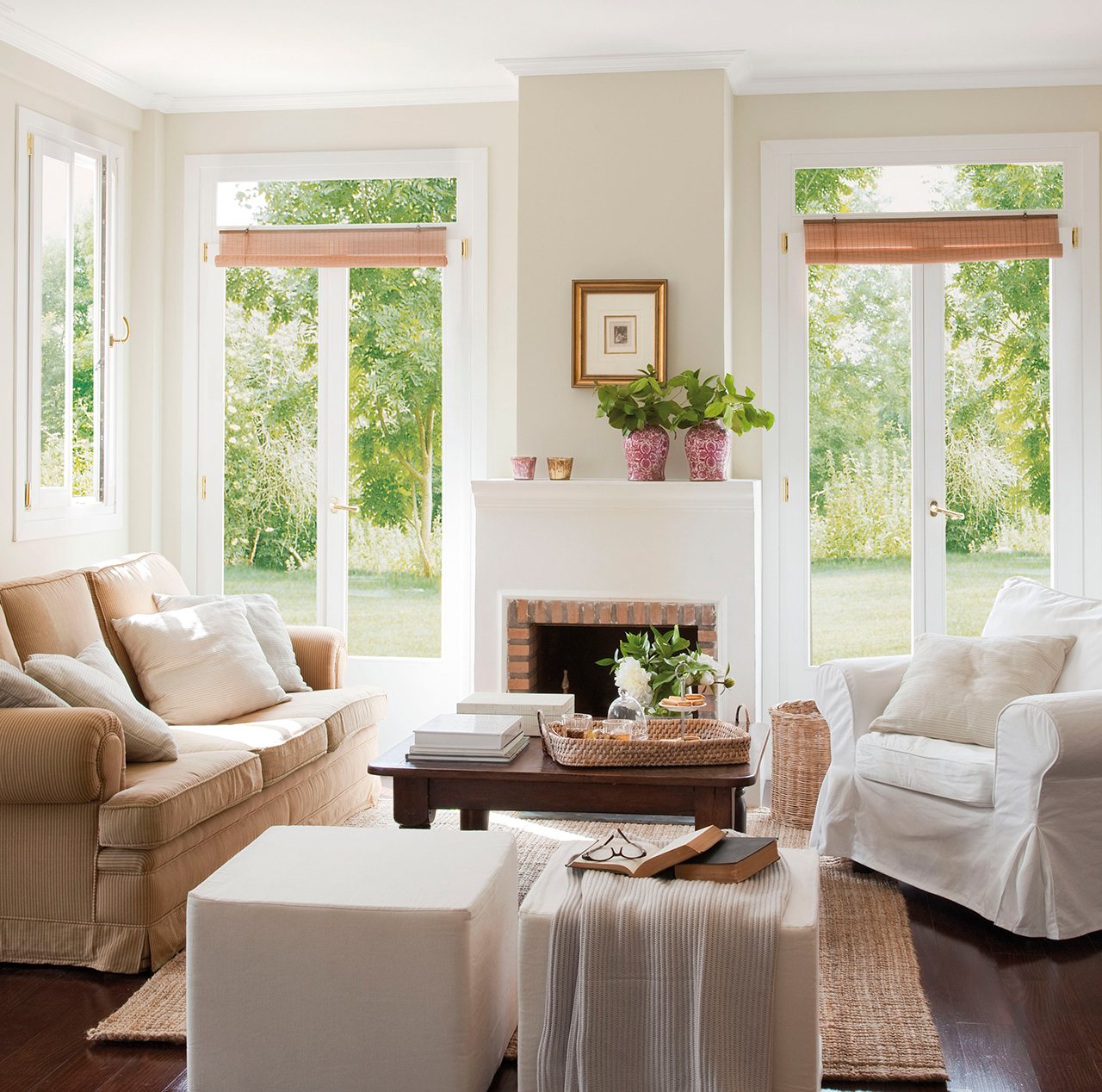 Salón con chimenea entre los grandes ventanales y sofás blancos. 