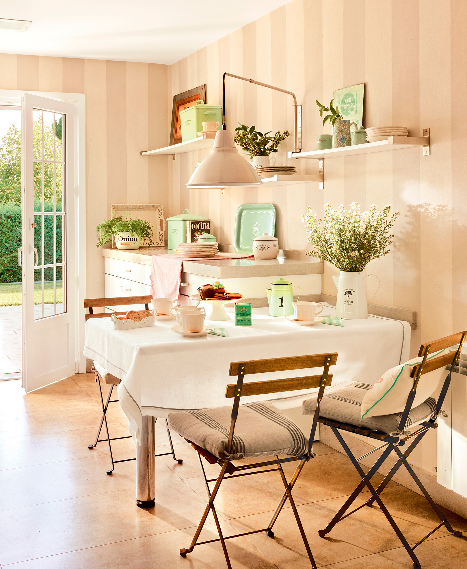 Comedor pequeño con papel pintado de rayas, mesa pegada a la pared y sillas plegables. 