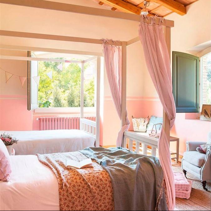 Dormitorio en rosa pastel y techo de madera, cama con dosel y cortinas rosa, banderines decorativos y plaid