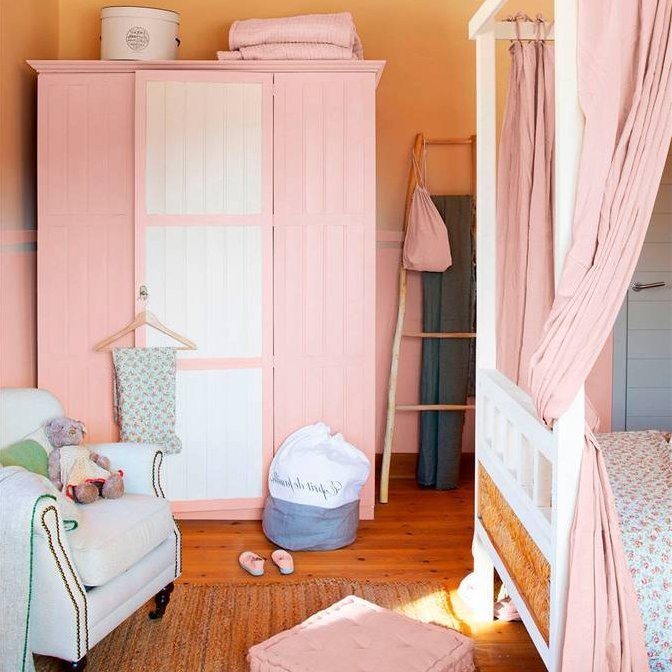 Dormitorio rosa pastel con armario, butaca y cama con dosel, pufs capitoné, escalera-colgador y alfombra