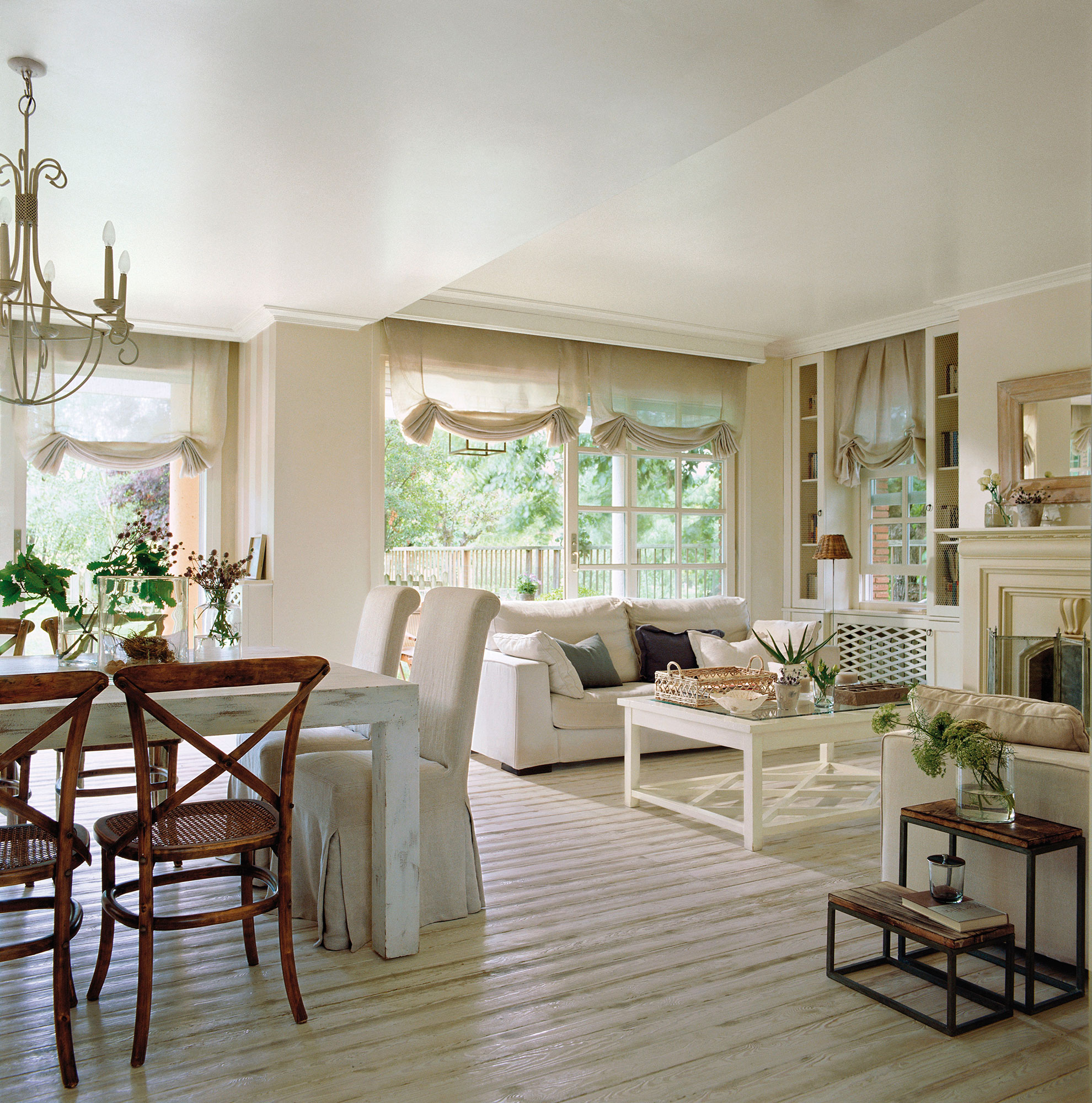 Salón comedor clásico con sofás y muebles de color blanco y chimenea.