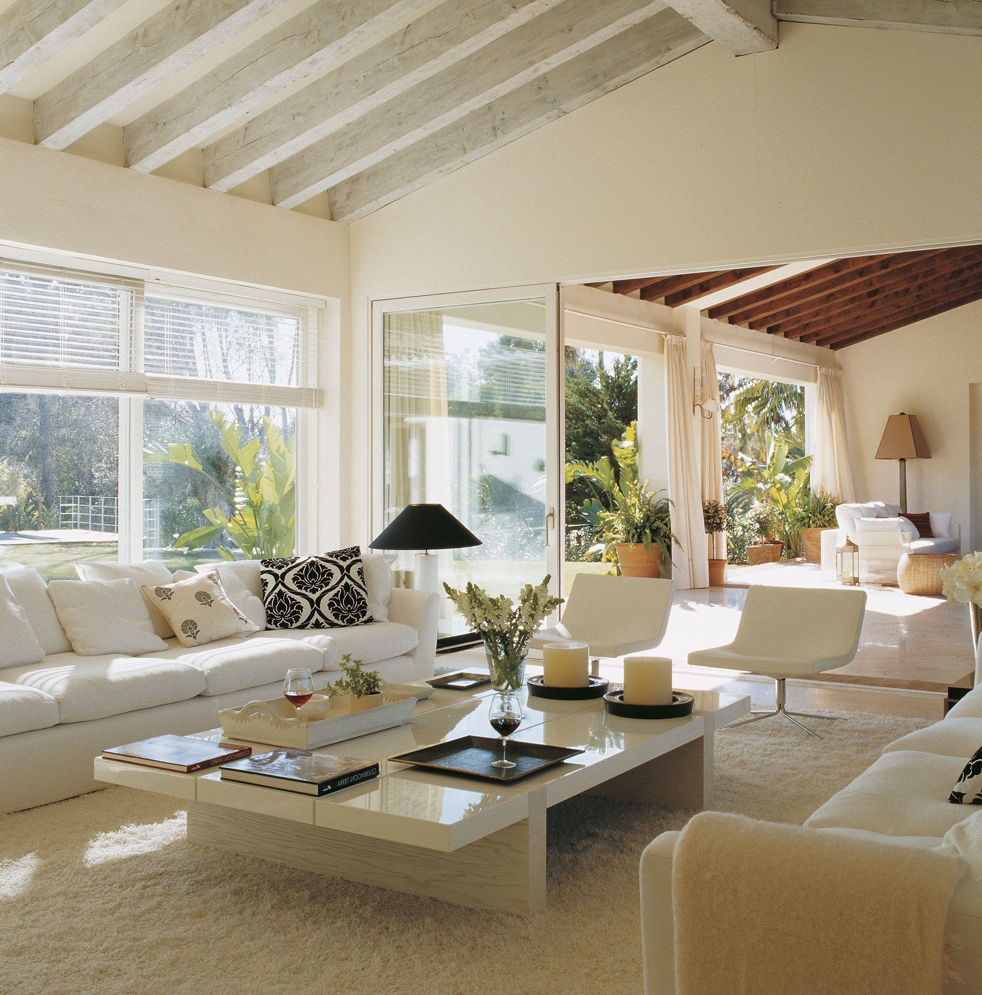 Salón moderno con sofás y muebles blancos abierto al porche.