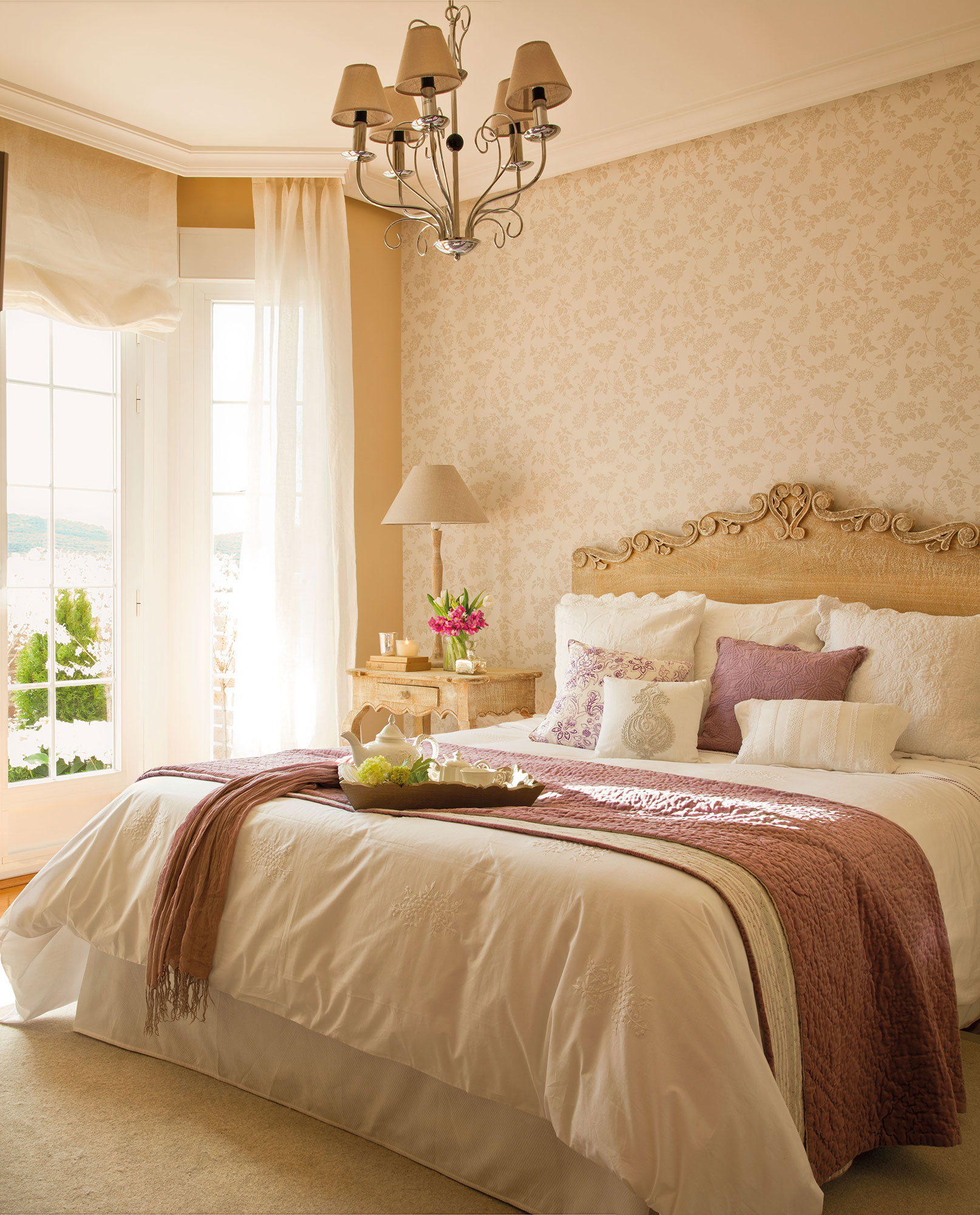 Dormitorio con estilo francés con papel pintado en el cabecero.