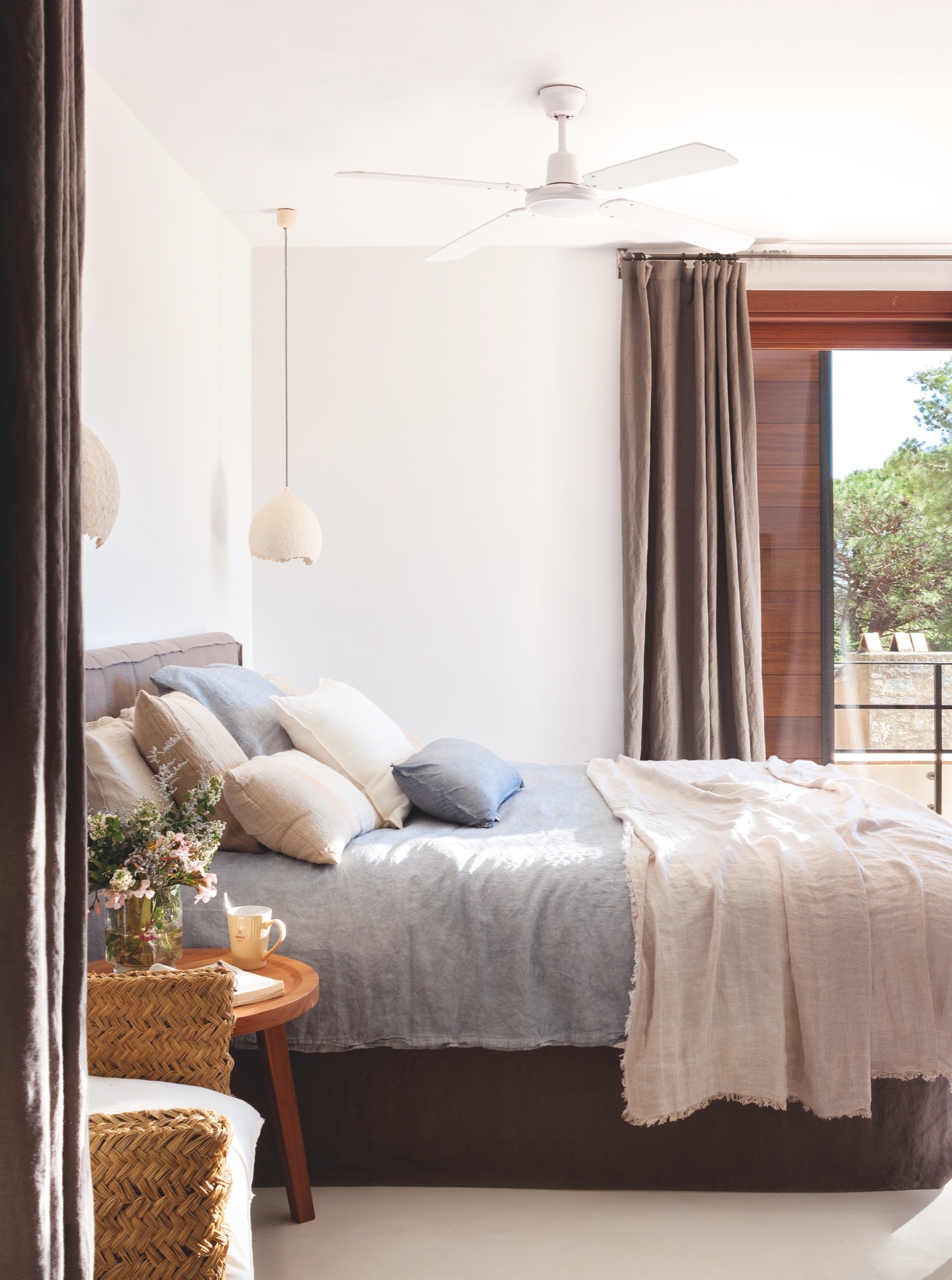 Dormitorio principal con cama azul y cortinas de lino. 