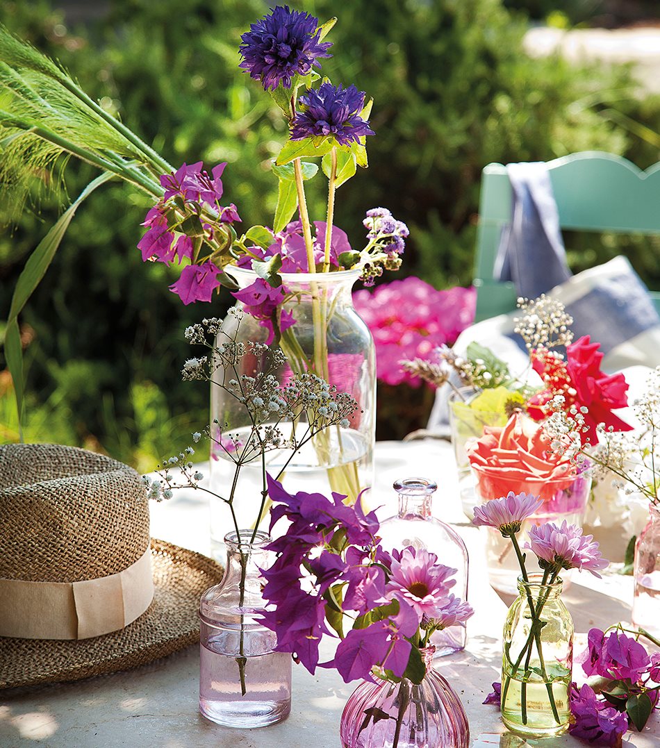 Diferentes jarrones con flores sobre mesa de exterior