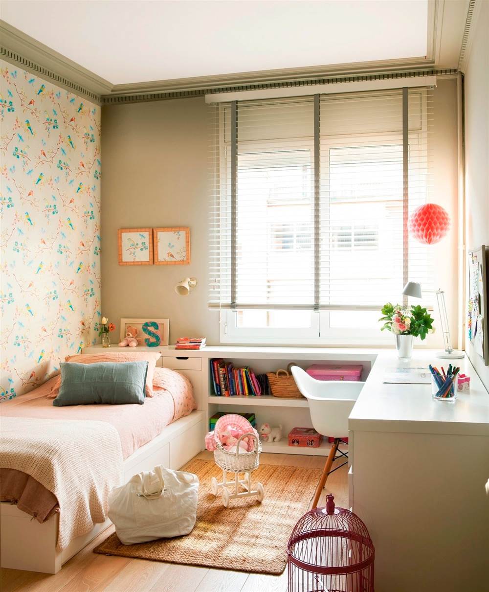 Dormitorio infantil con papel pintado en una de las paredes, escritorio a medida con silla Eames que hace L transformándose en cabecero con estantería