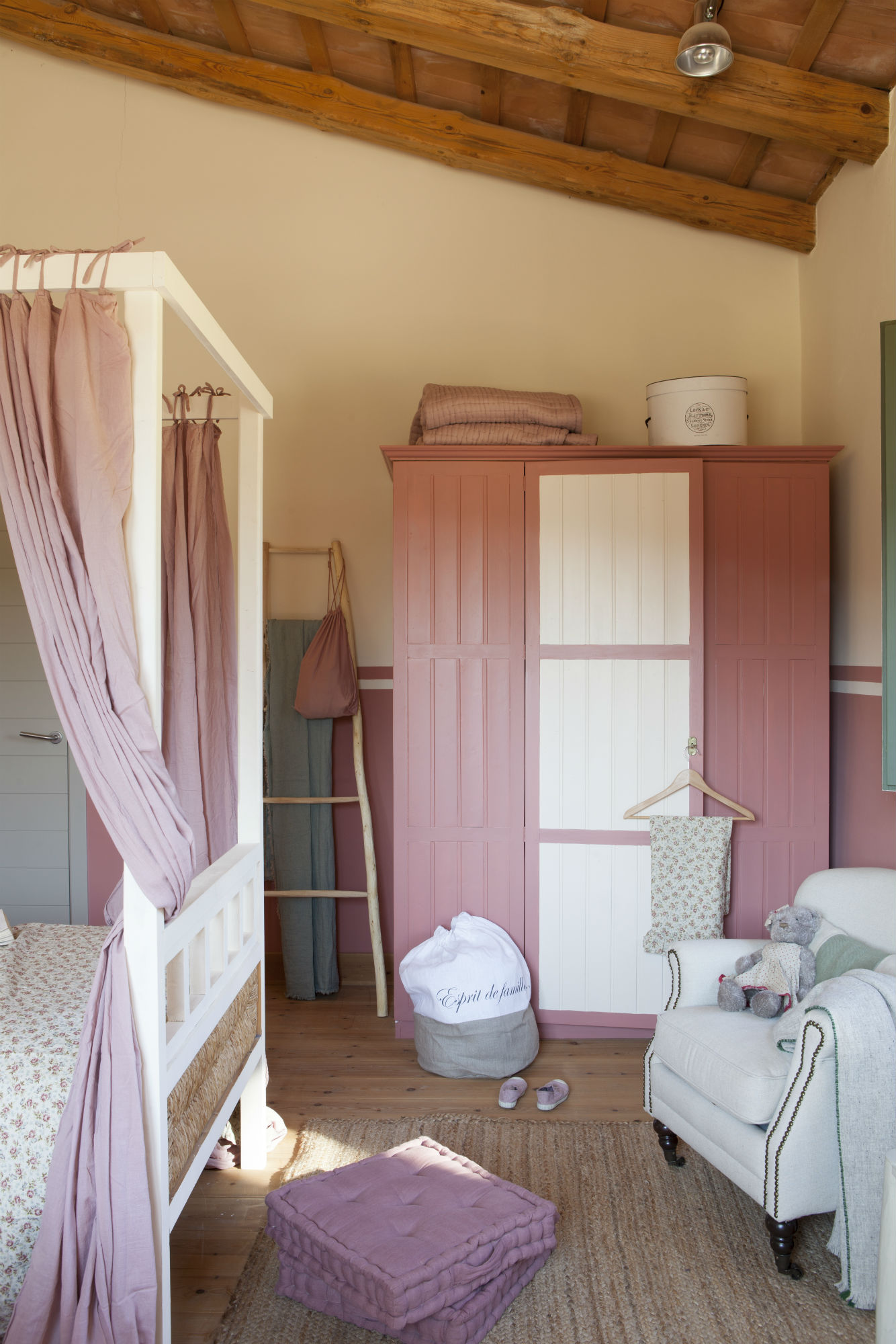Habitación infantil con armario rosa y cama con dosel. 