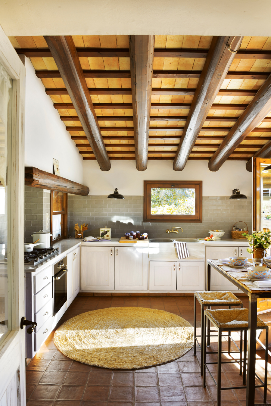 Cocina rústica con suelos de barro y techos con vigas de madera. 
