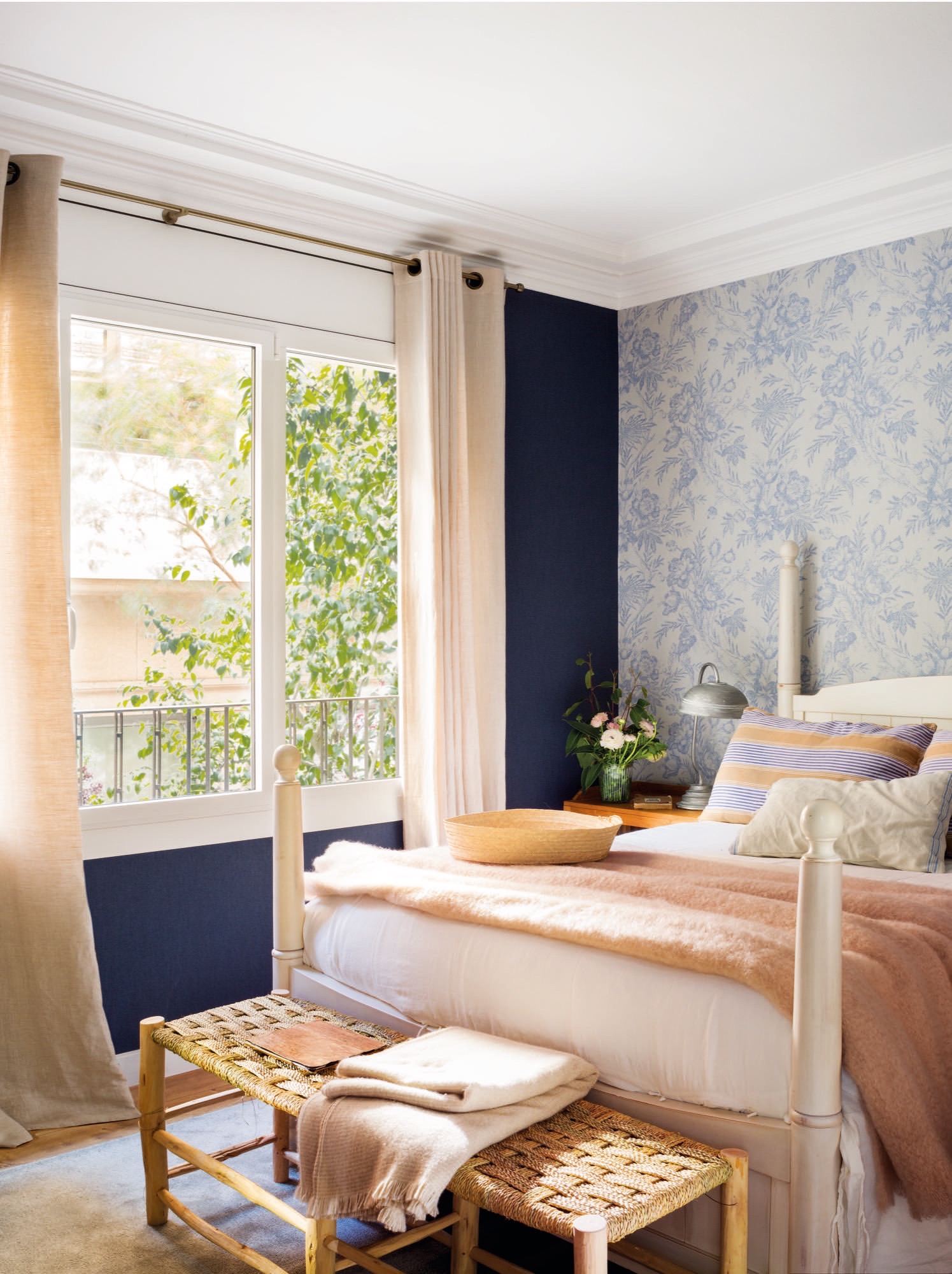 Dormitorio con pared de la ventana en azul y la del cabecero con papel pintado. 