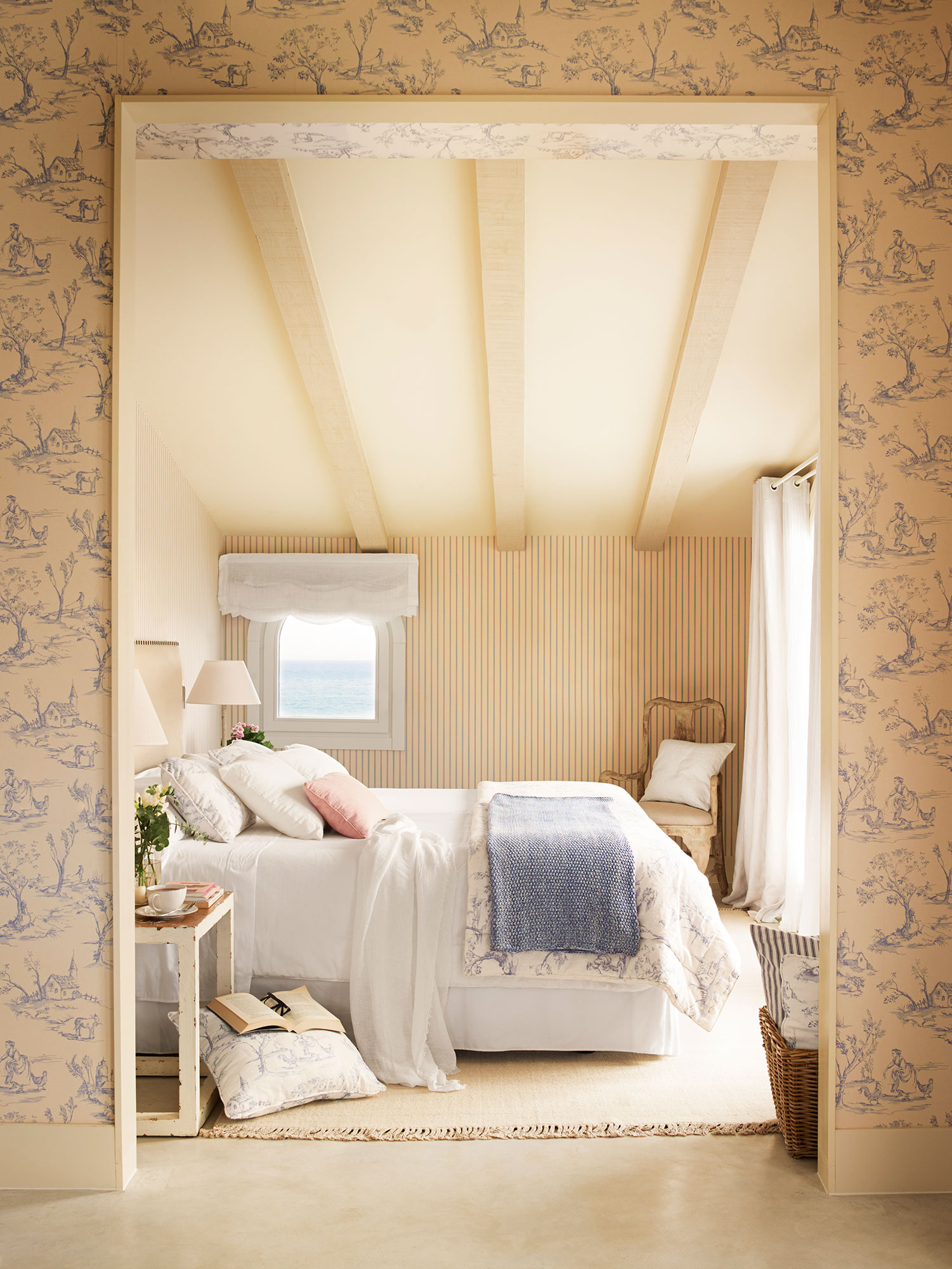 Dormitorio de verano con ropa de cama beige y papel pintado de rayas.  