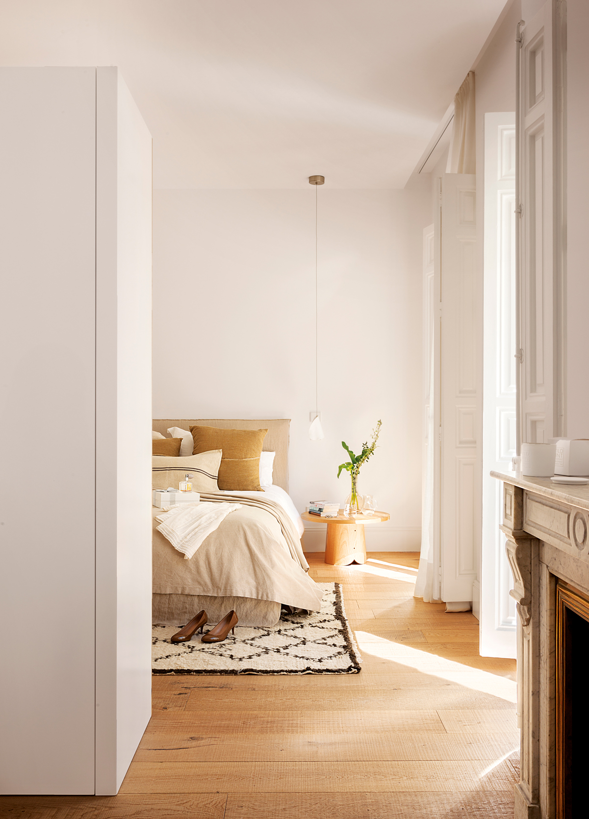 Dormitorio sencillo con alfombra, cama y lámpara colgante. 