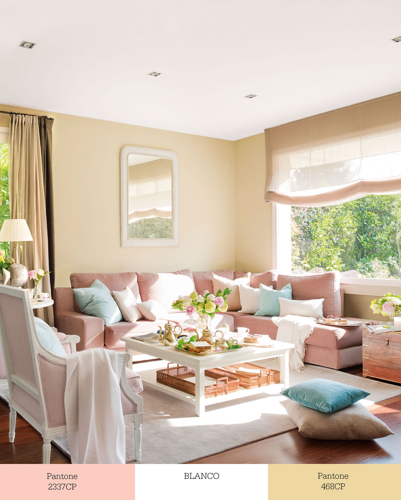 Salón con paredes beige, sofás rosas y cojines en color blanco. 