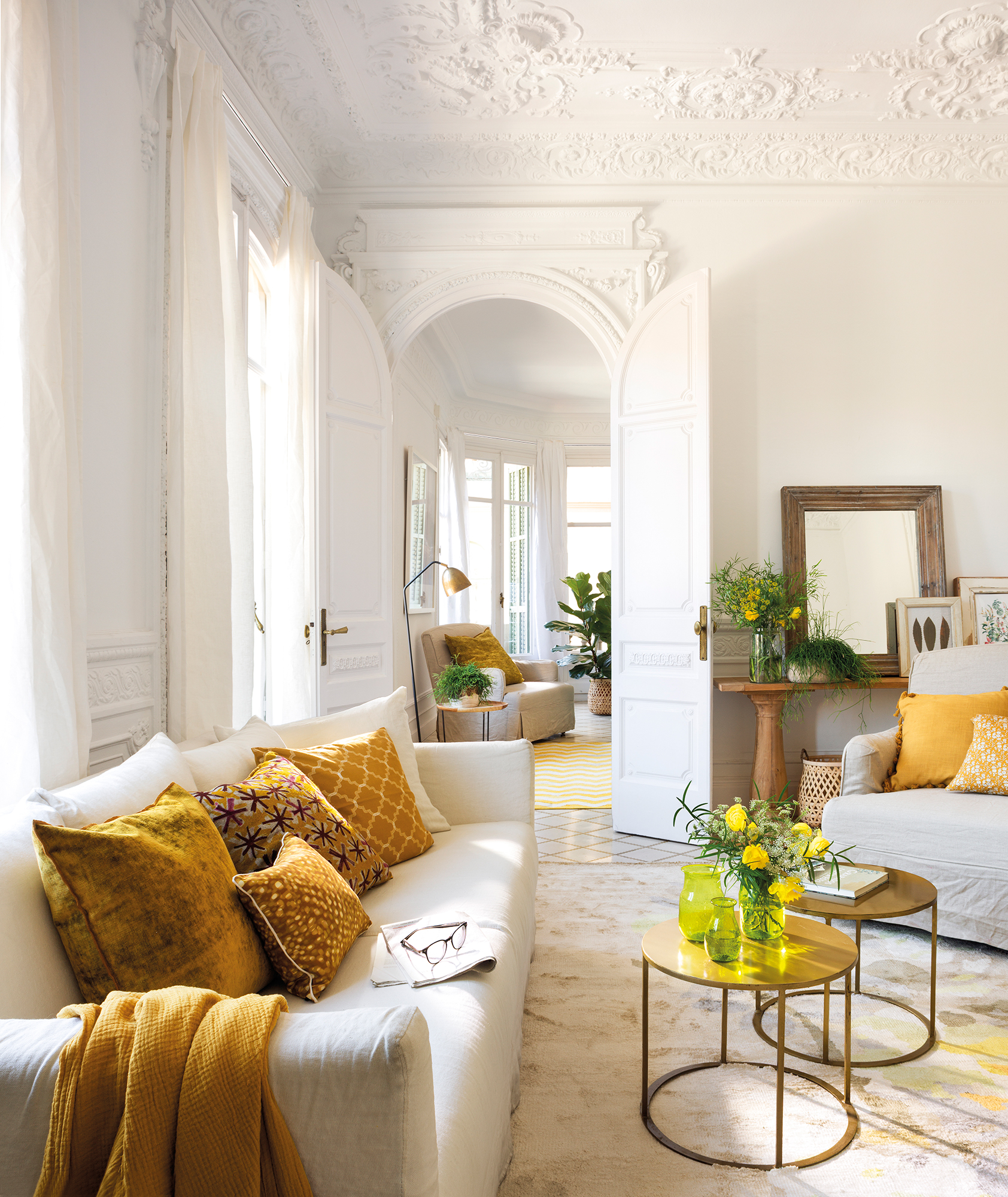 Salón blanco con sofá y butaca blanca con cojines amarillos y dorados.