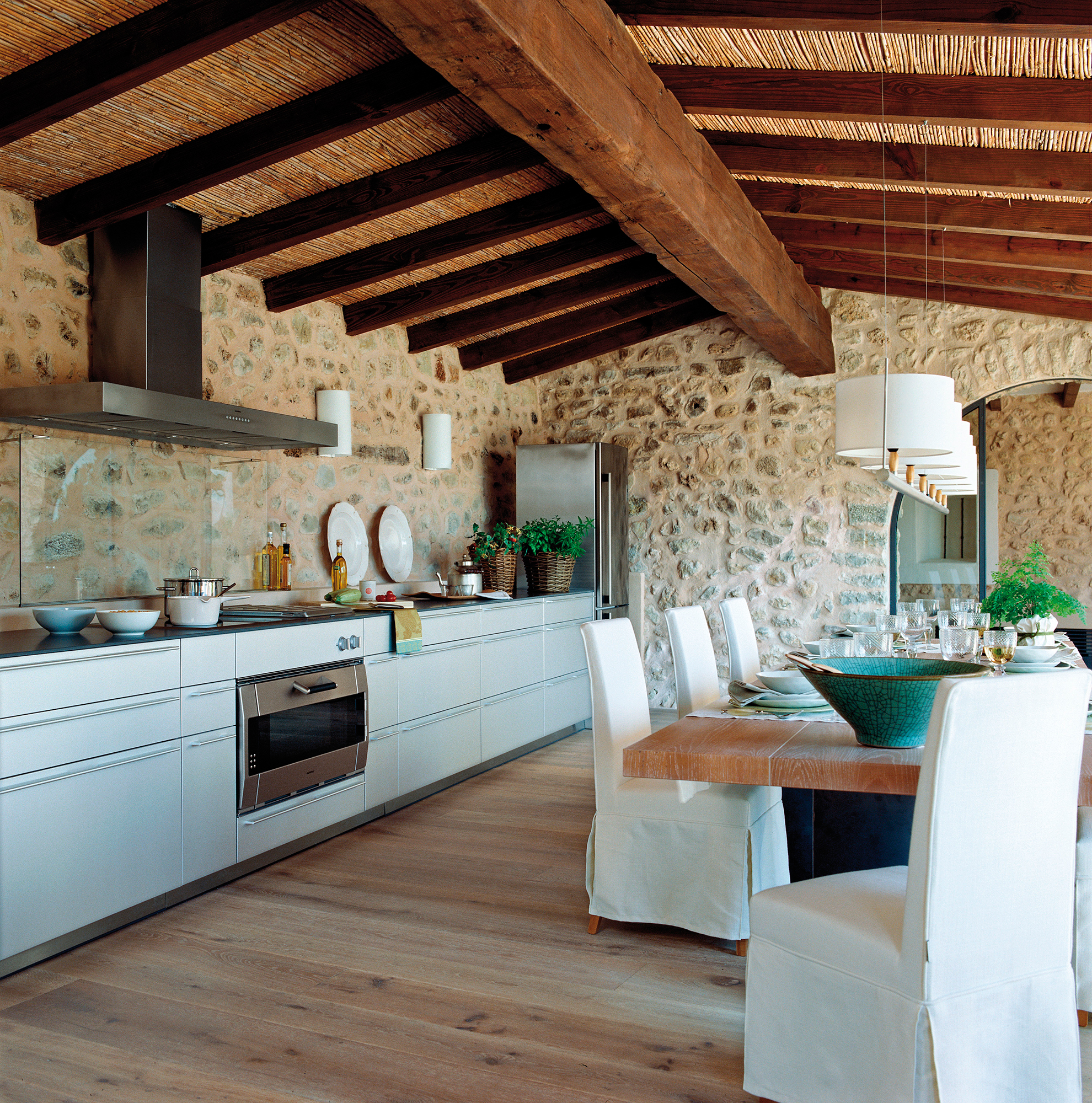 Cocina con muebles modernos y paredes de piedra.