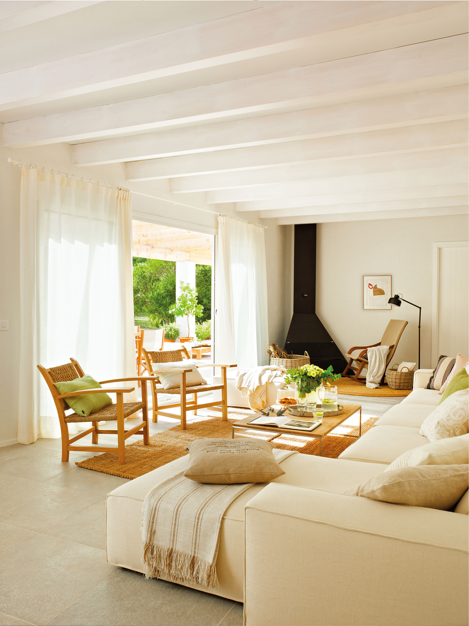 Un salón relajante y natural con un sofá blanco, alfombra de fibras y chimenea moderna. 