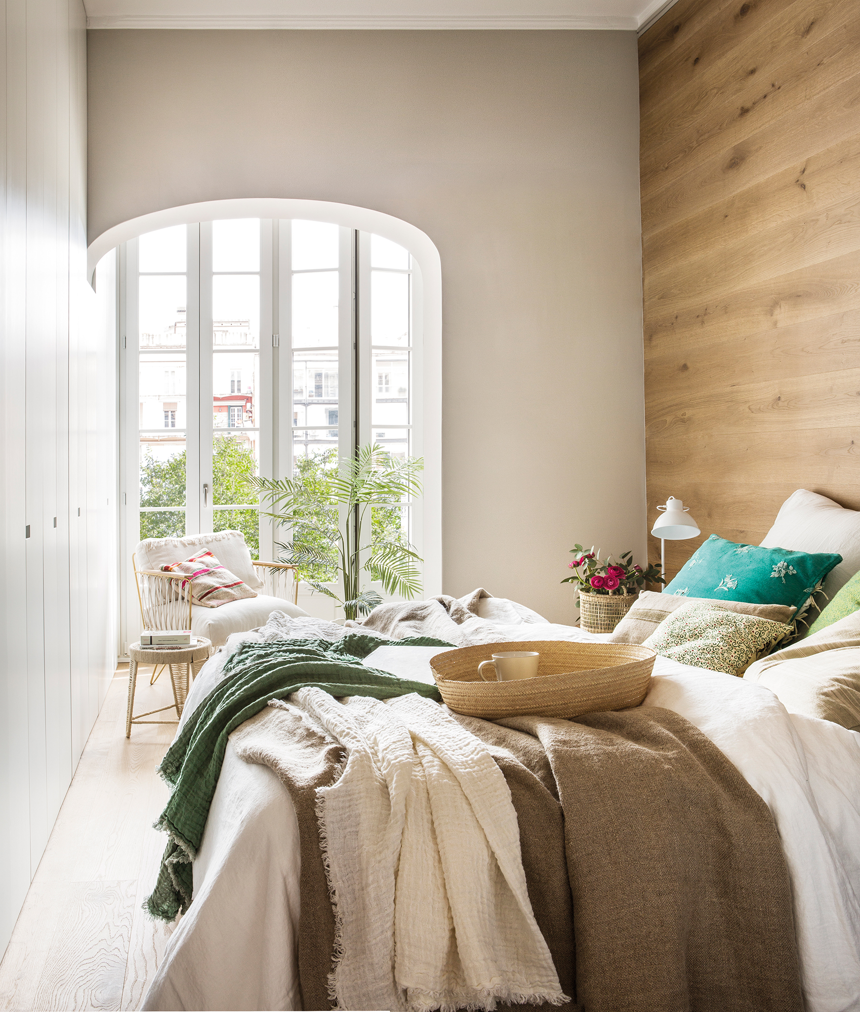 Dormitorio moderno con pared en madera y rincón de lectura. 