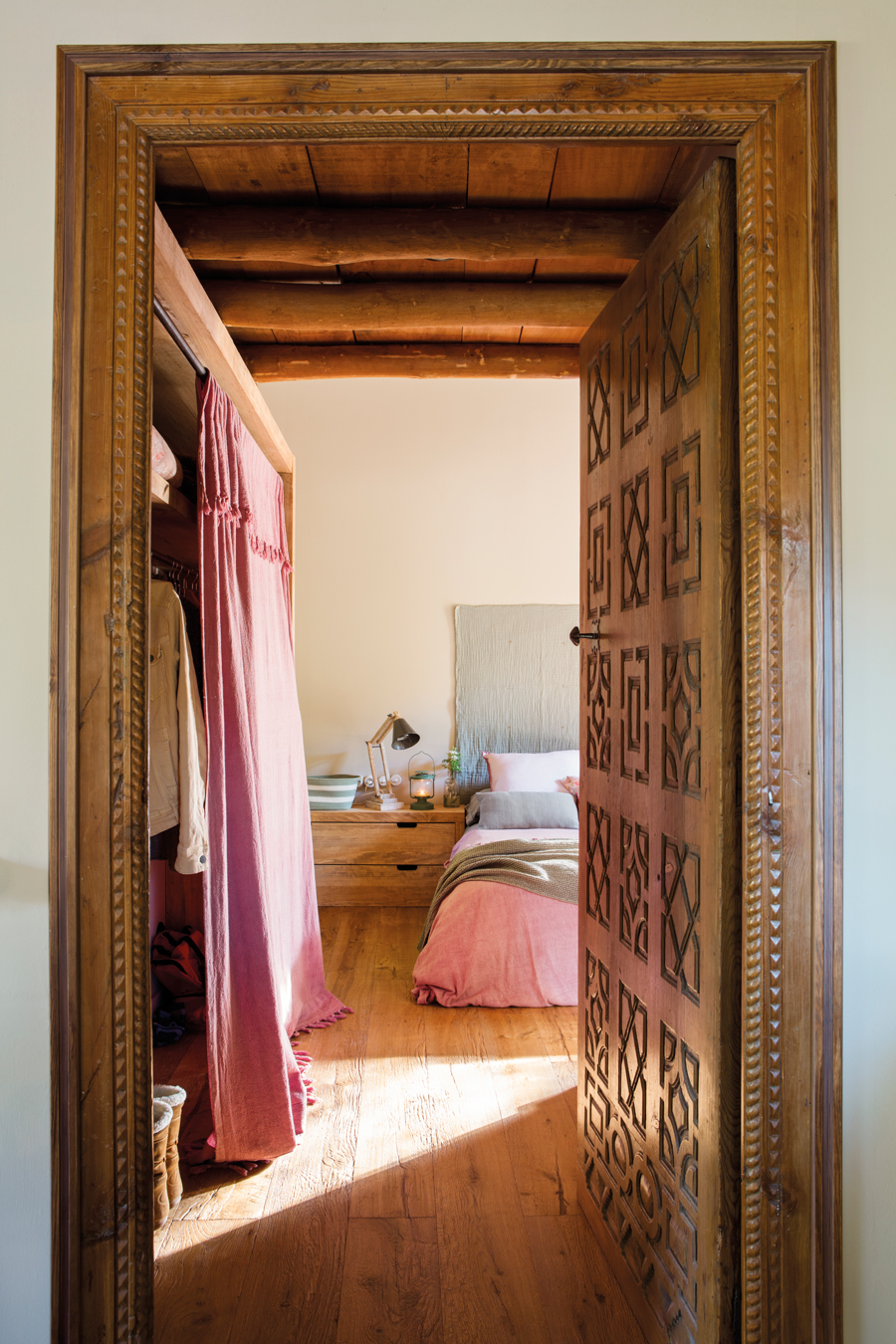 Dormitorio de casa rústica con puerta antigua recuperada y armario cerrado con cortinas