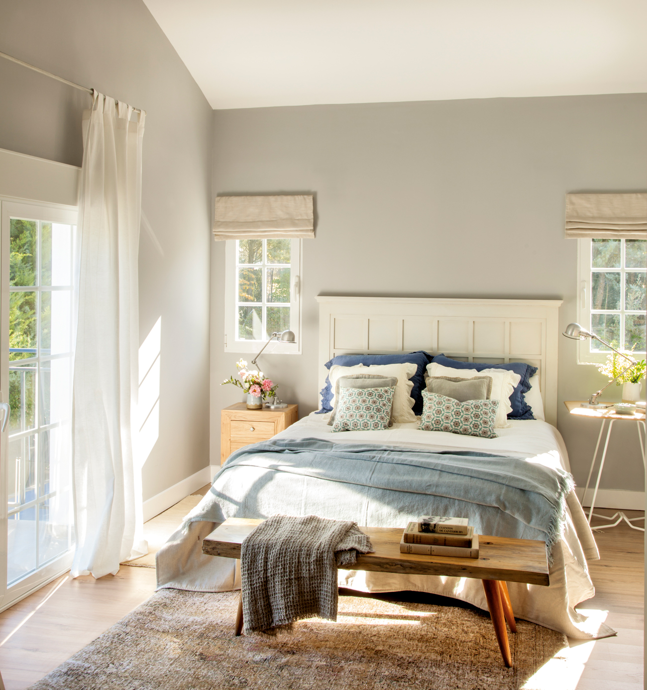 Dormitorio en blanco y azul con banco de madera a pie de cama