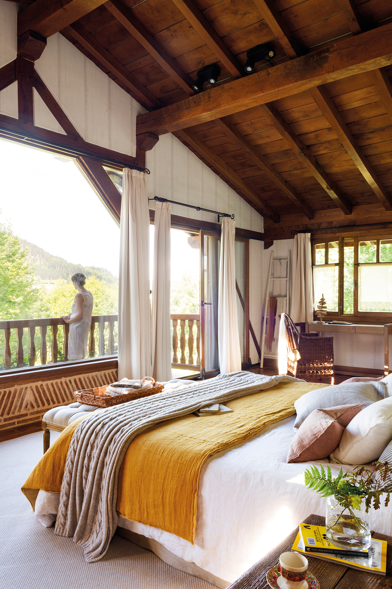 Dormitorio rústico con techos abuhardillados de madera y ropa de cama blanca y mostaza. 