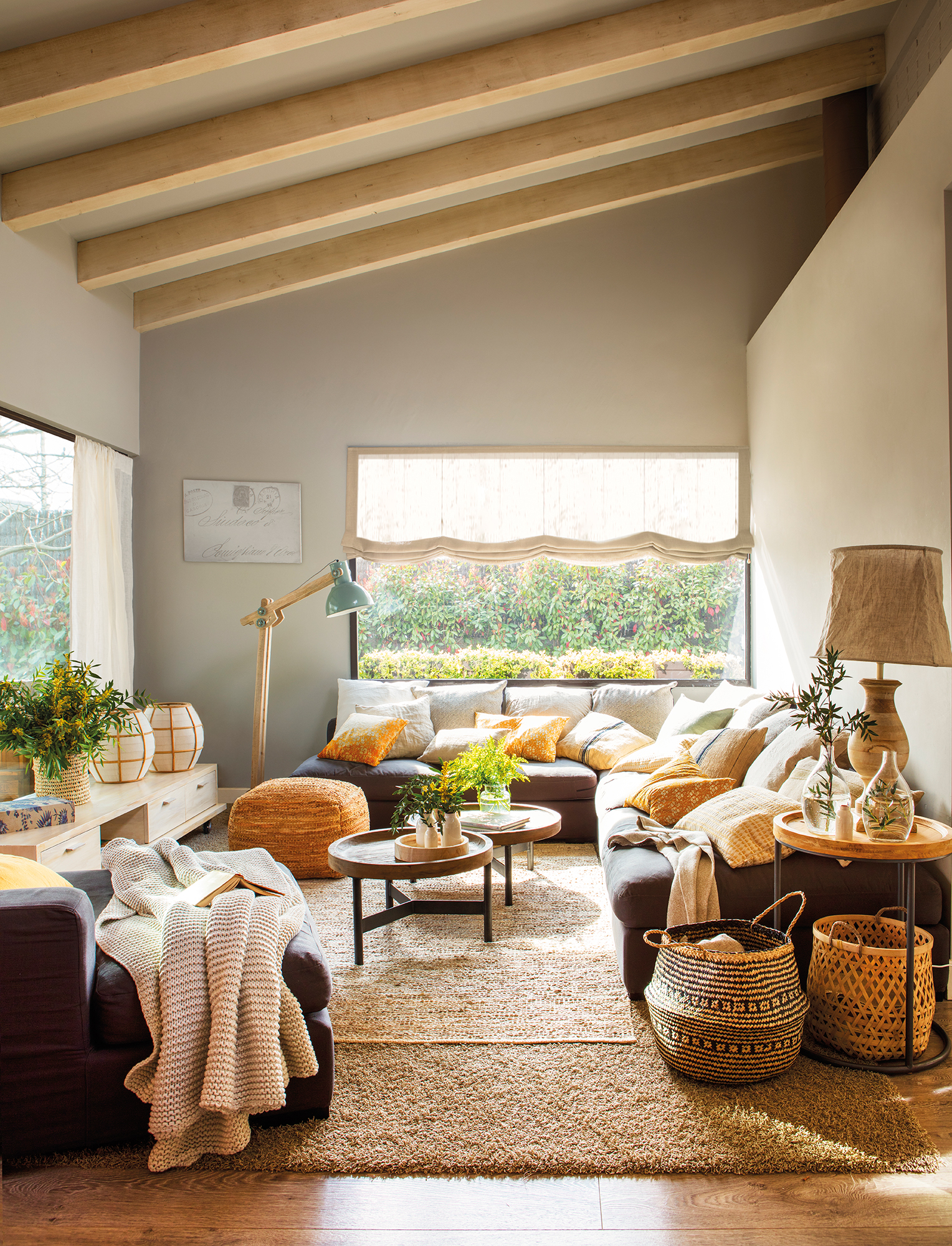 Salón rústico con sofá esquinero de color gris y complementos de fibras naturales. 