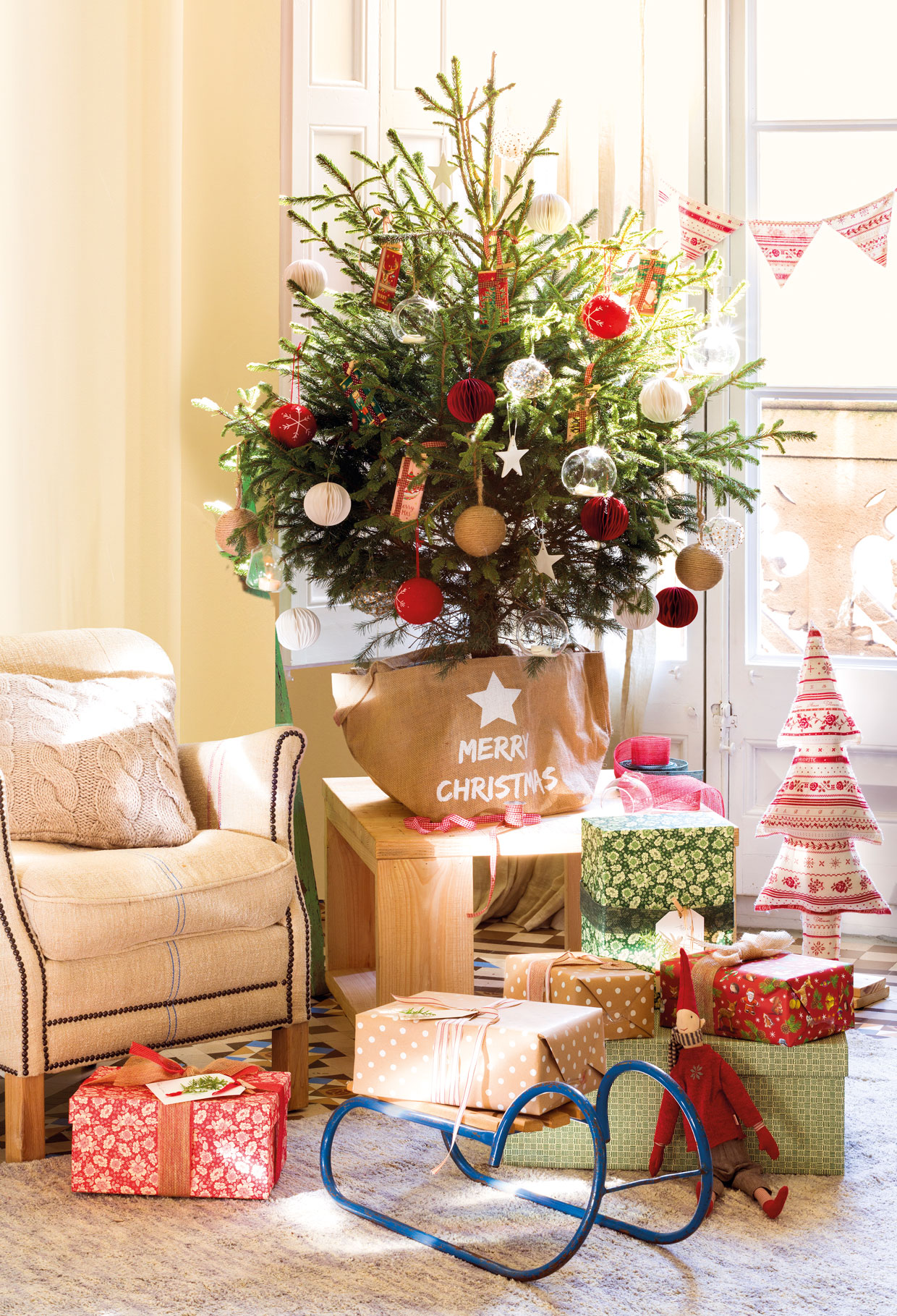 Salón con mesa auxiliar de madera, adornos navideños y mini árbol de Navidad.
