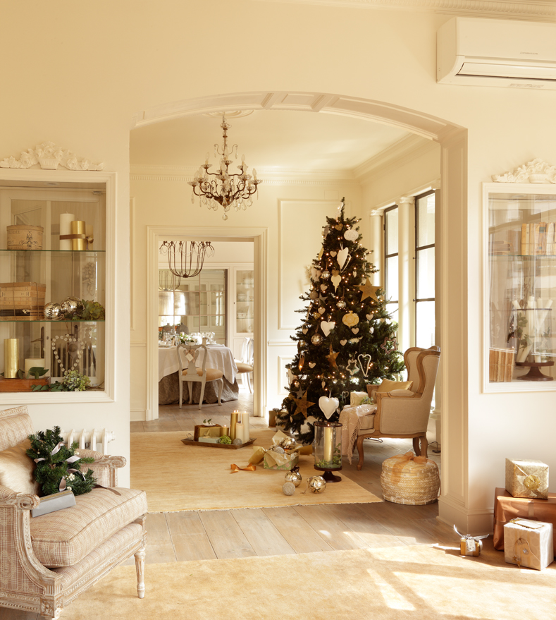 Distribuidor con molduras, pavimento de madera y árbol de Navidad decorado en dorado.
