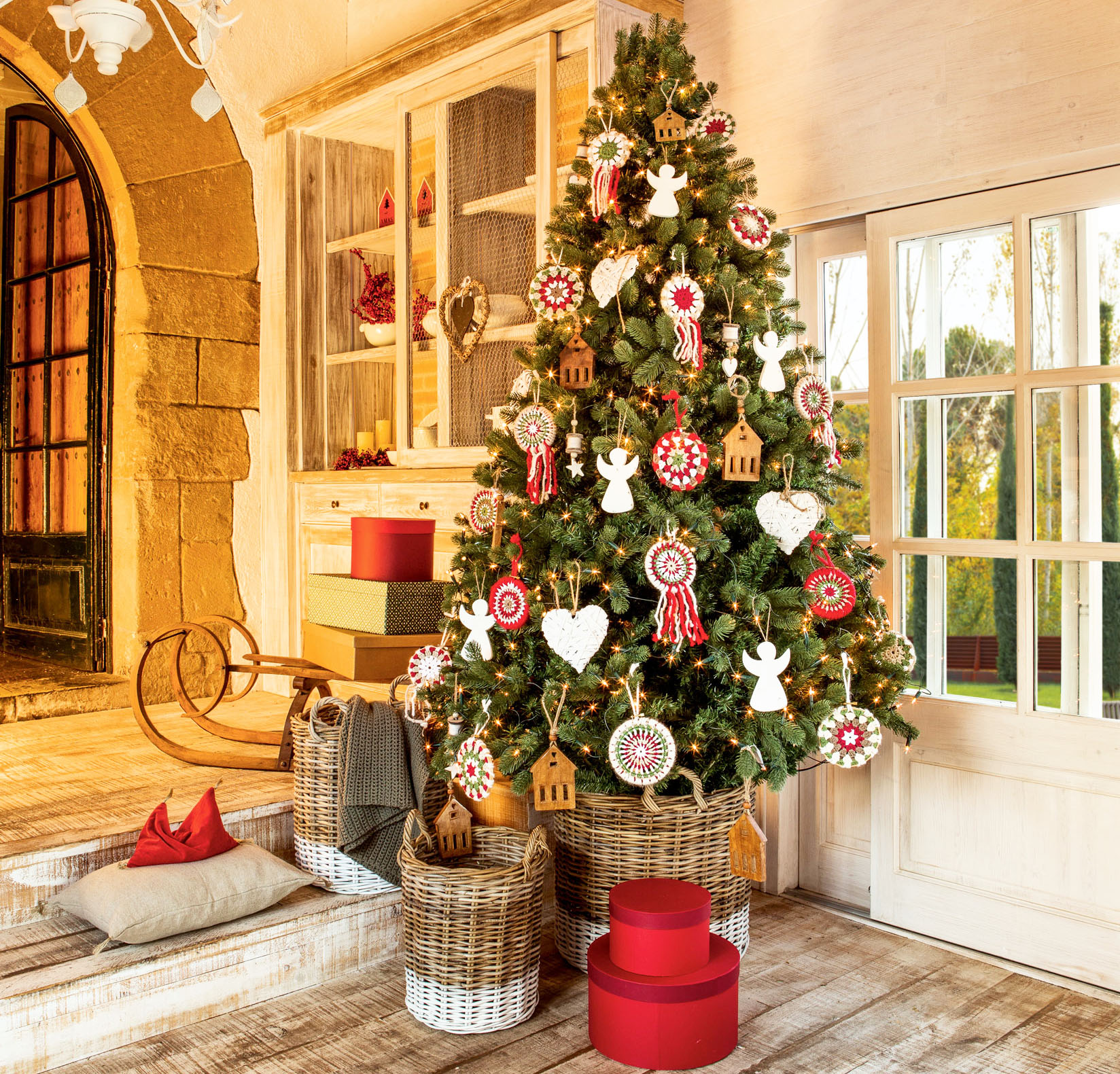 Recibidor con suelo de madera y árbol de Navidad en cesta con adornos navideños a ganchillo. 