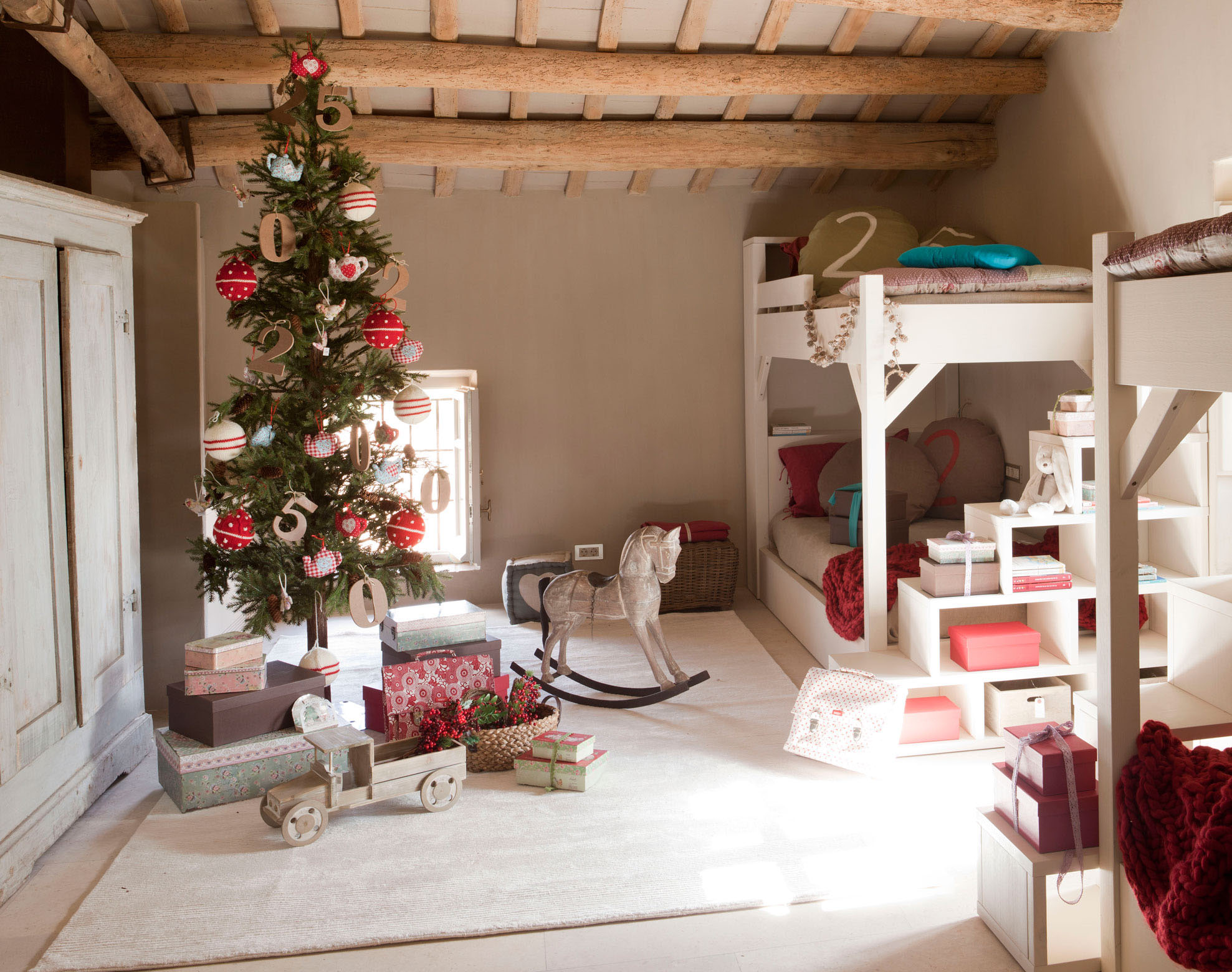 Dormitorio infantil con litera blanca, vigas en el techo y árbol de Navidad slim con regalos.