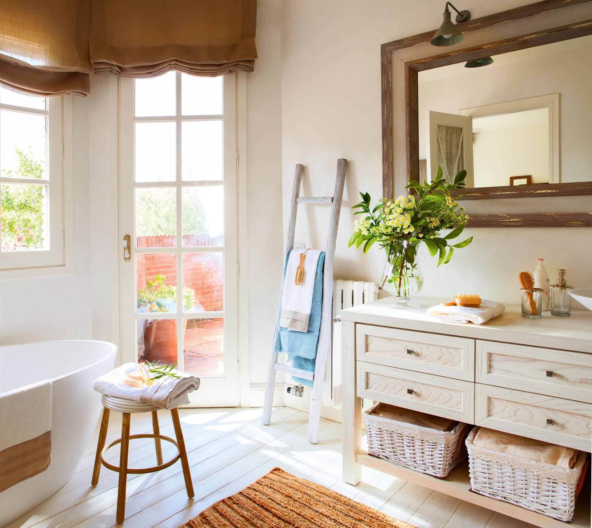 Baño con mueble blanco, bañera ovalada, escalera toallero tapando el radiador.