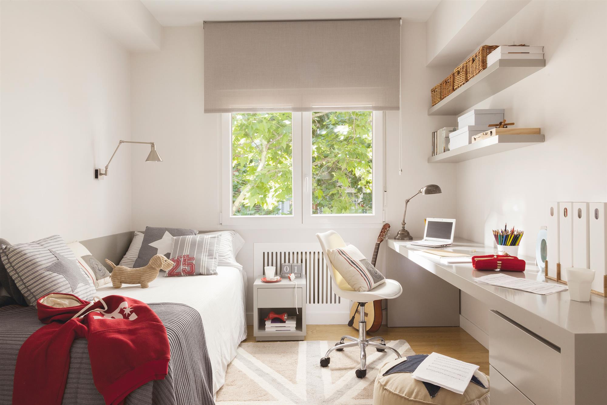 Dormitorio juvenil con cama, escritorio y cubre radiador bajo la ventana.