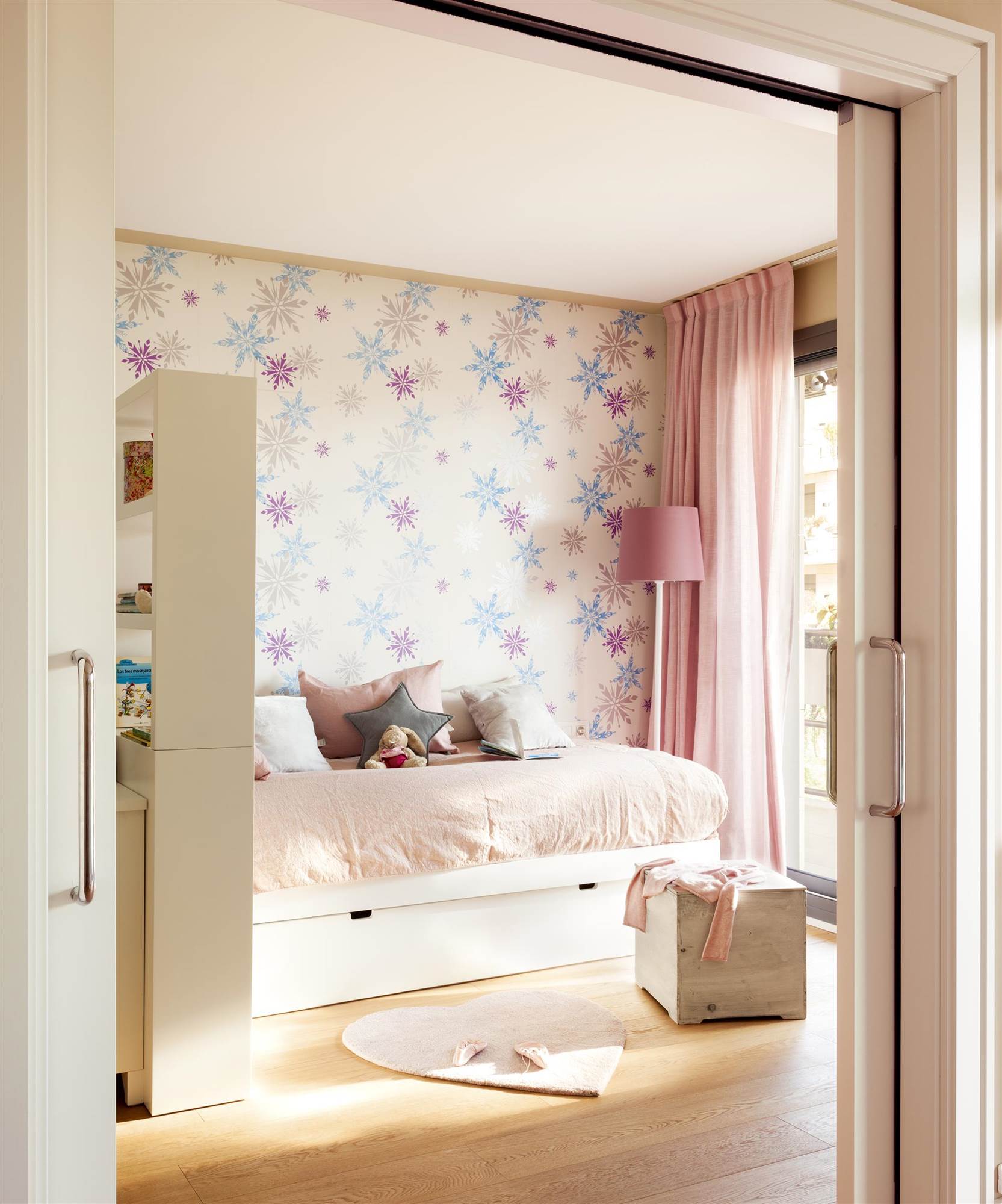 Dormitorio infantil con papel pintado con estrellas y cama con cajones.