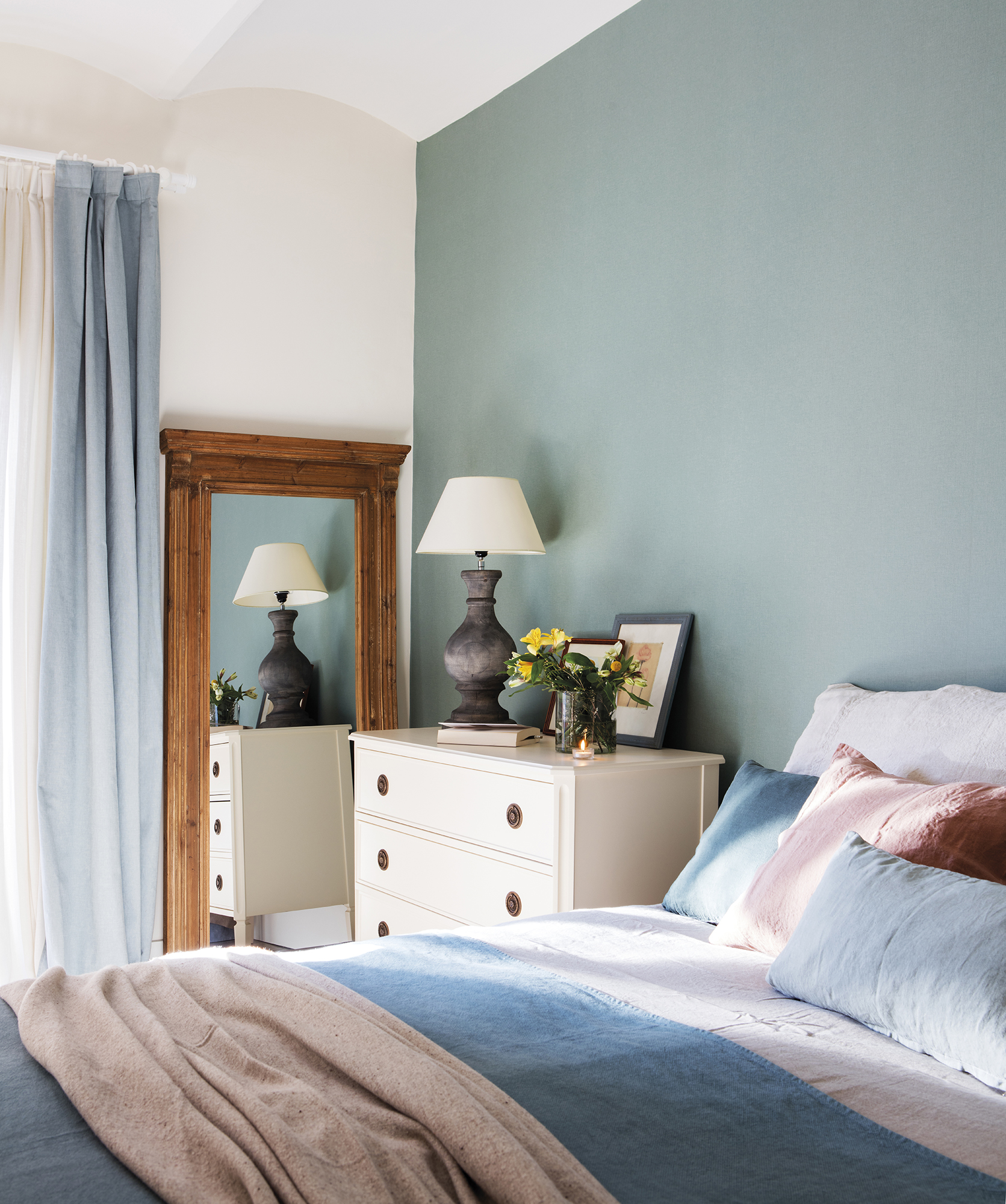 Dormitorio con pared del cabecero con papel pintado y cómoda como mesita de noche. 