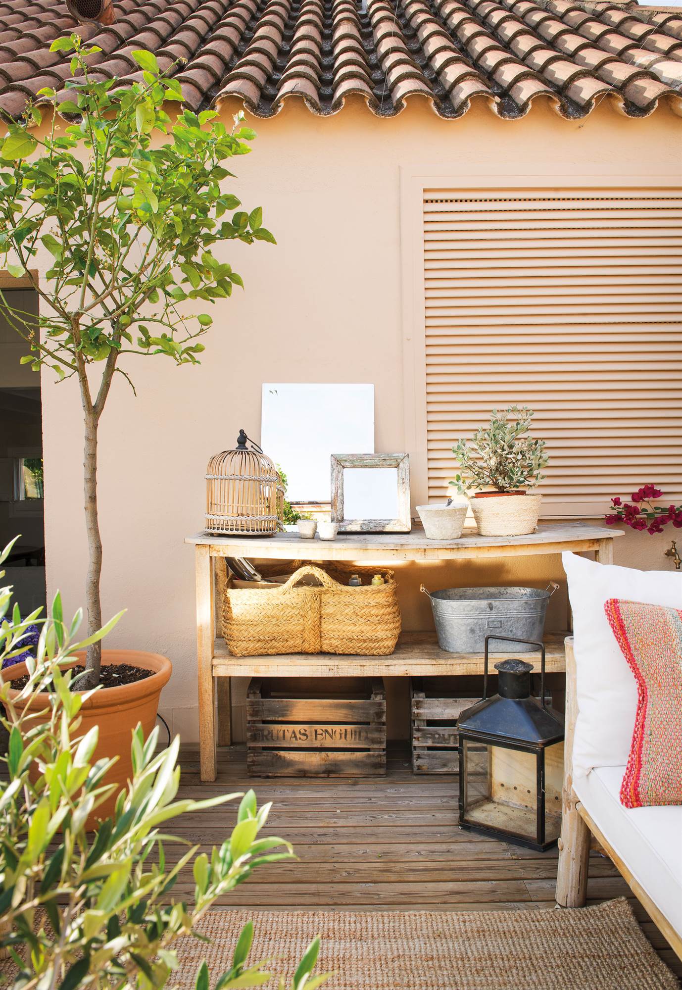 Terraza con pavimento de madera, mueble para jardinería y limonero en maceta.