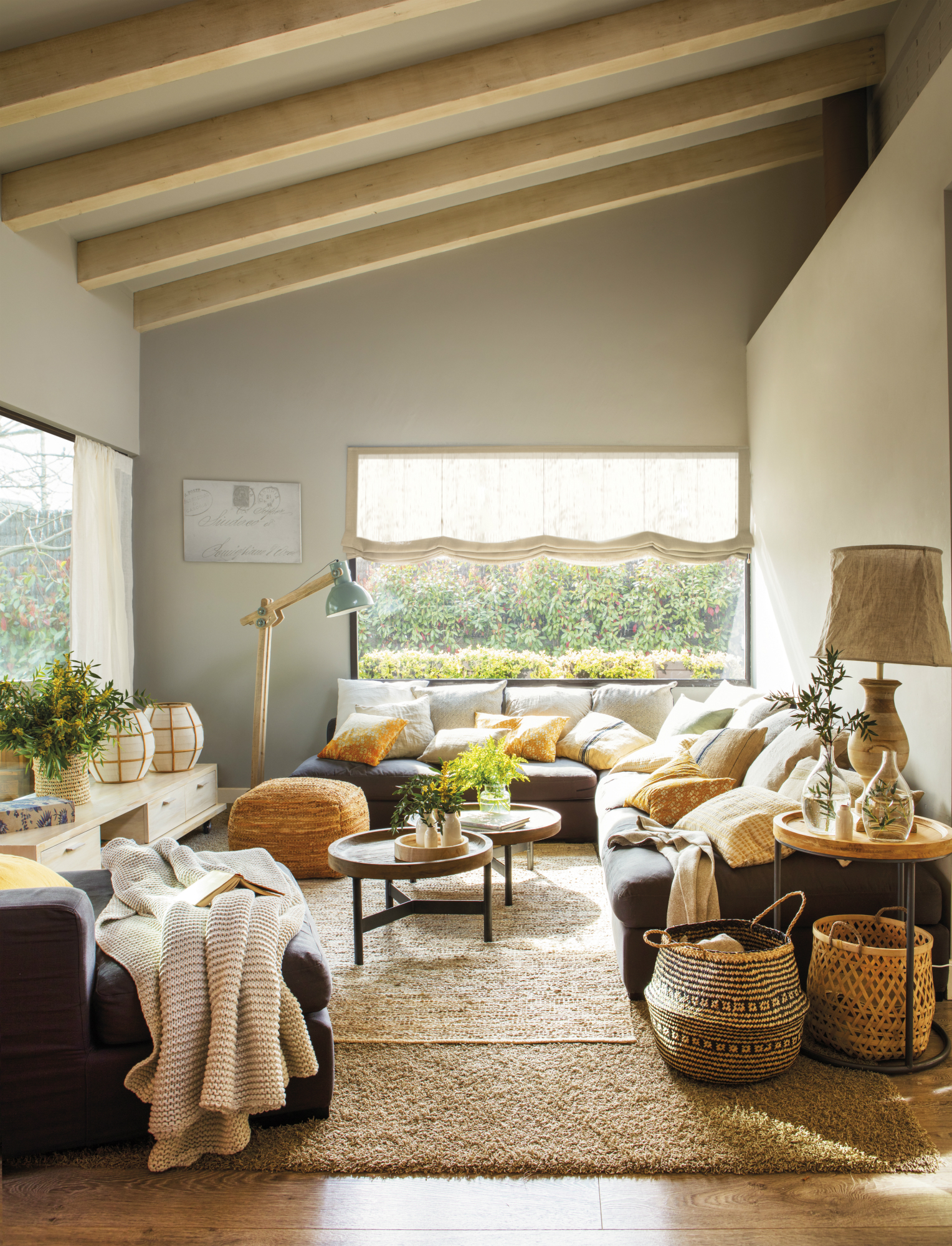 Salón moderno abuhardillado con sofá rinconero, vigas en el techo y alfombra.