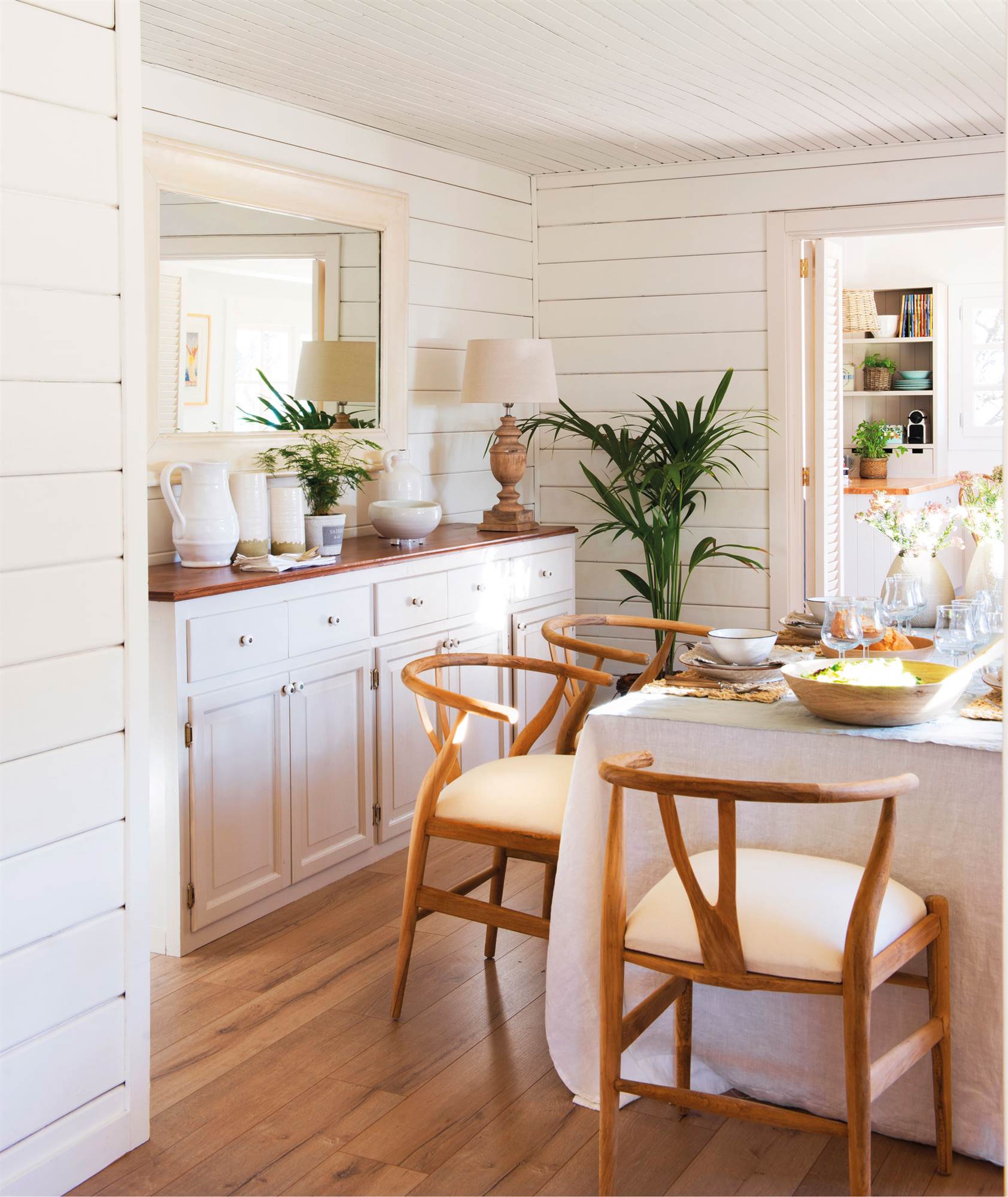 Comedor decorado en blanco con listones de madera en las paredes.