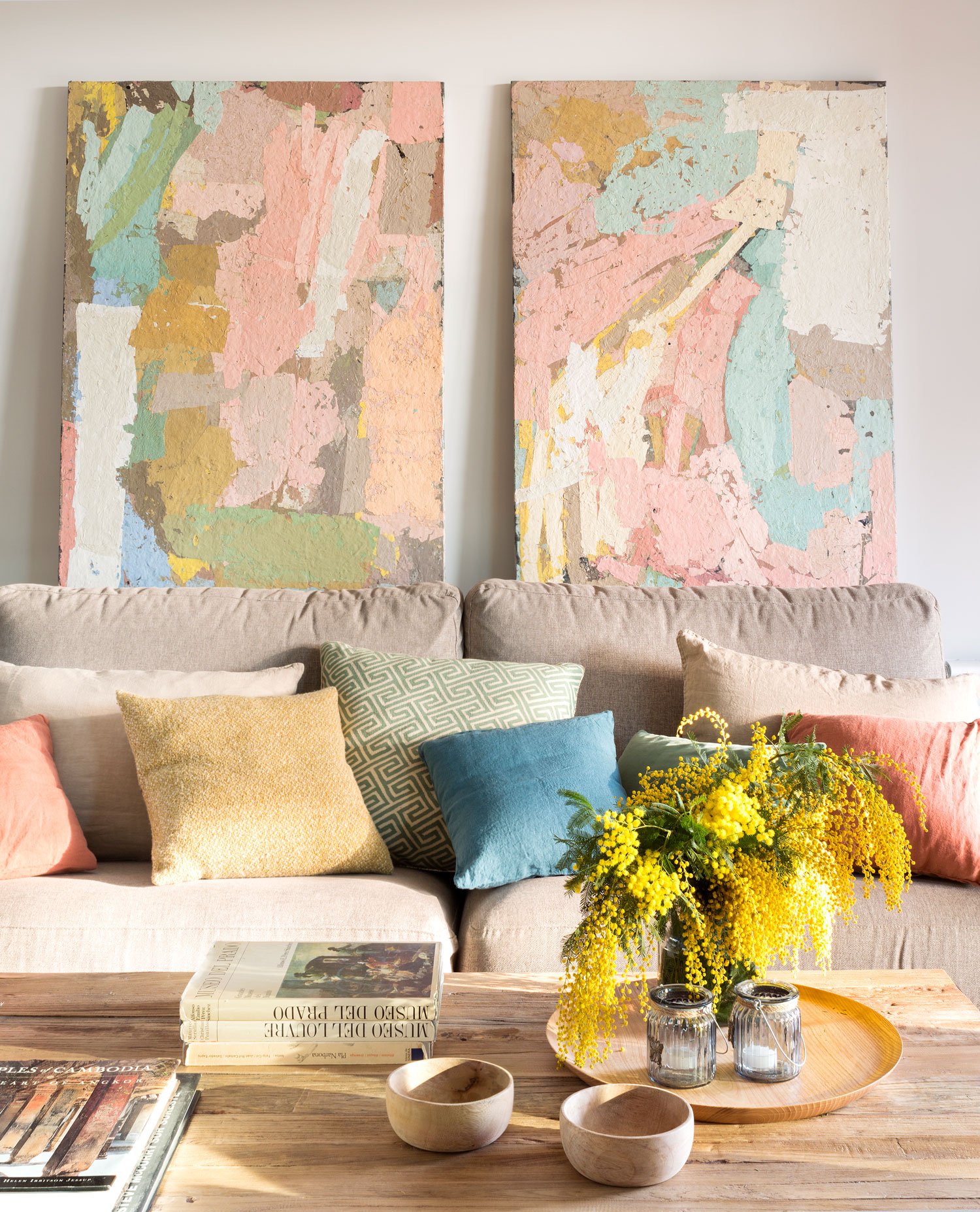 Salón con sofá beige, cuadros abstractos y mesa de centro de madera-