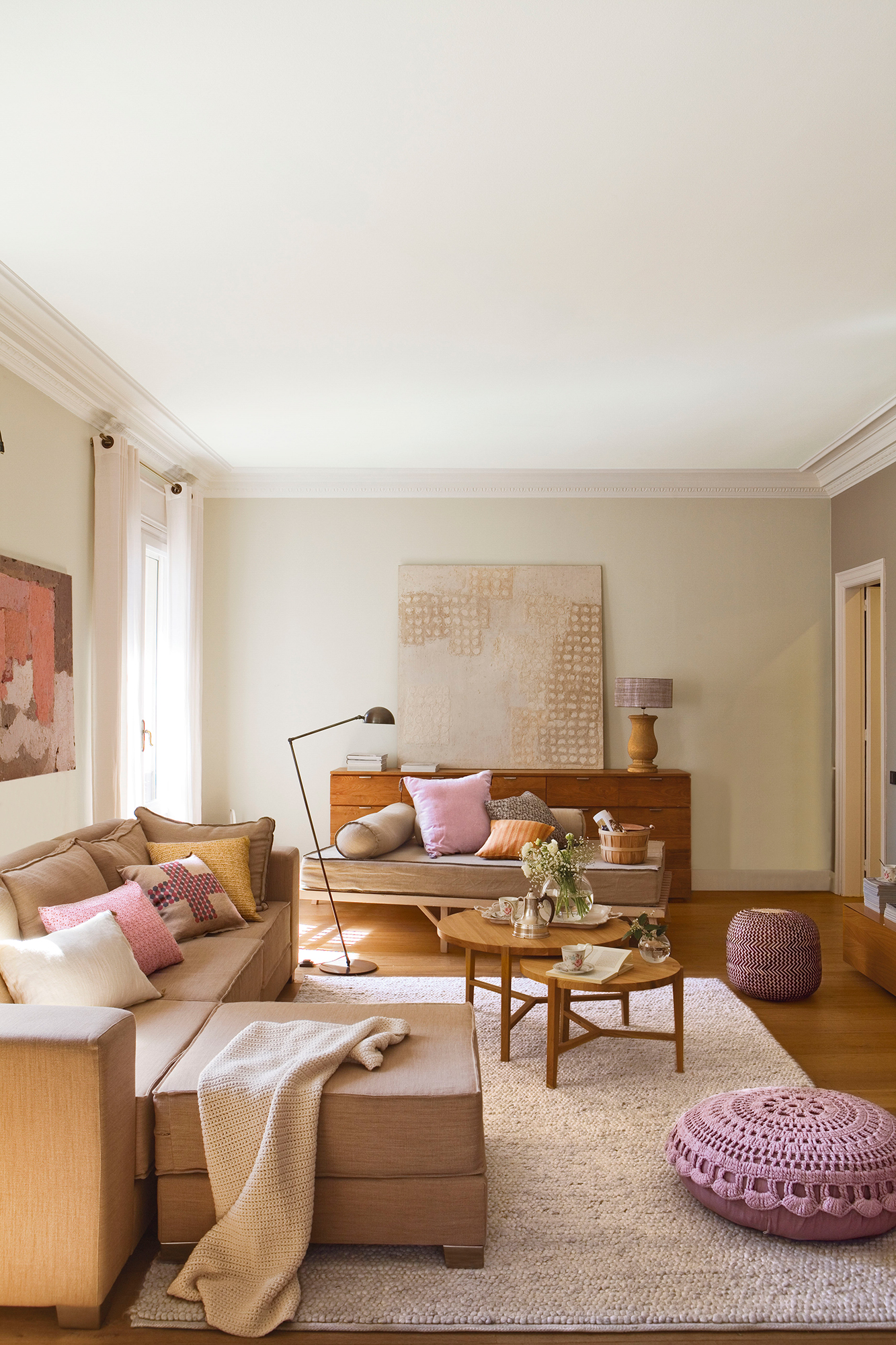 Salón con alfombra gris puff y cojines morados y sofá con chaise longue.