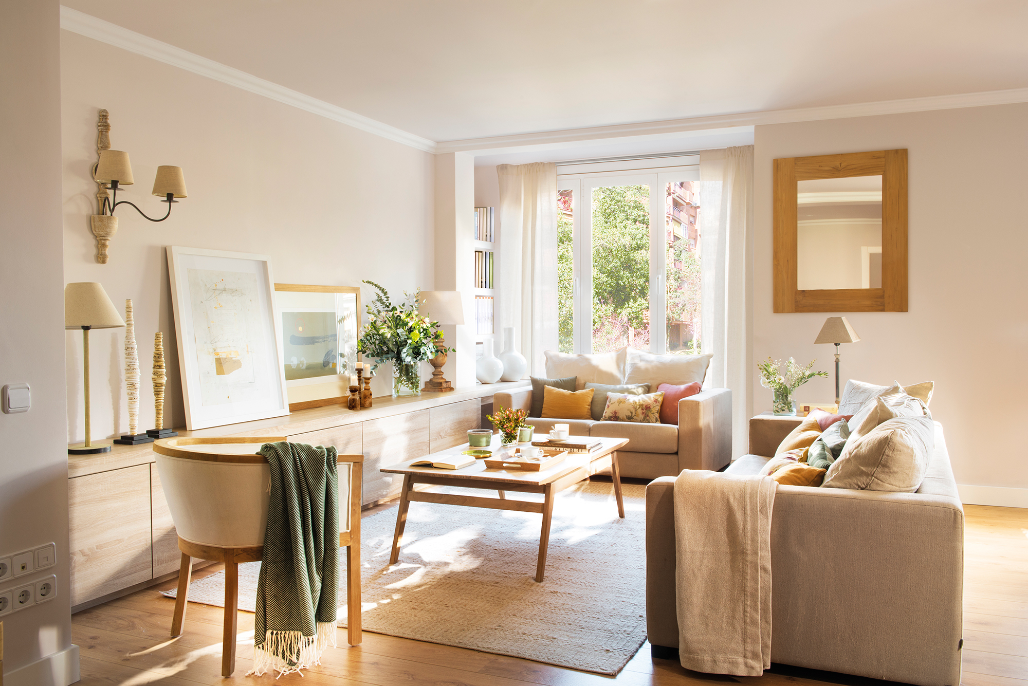 Salón moderno en tonos claros con mueble de madera, cuadros decorativos, alfombra y sofás grises.