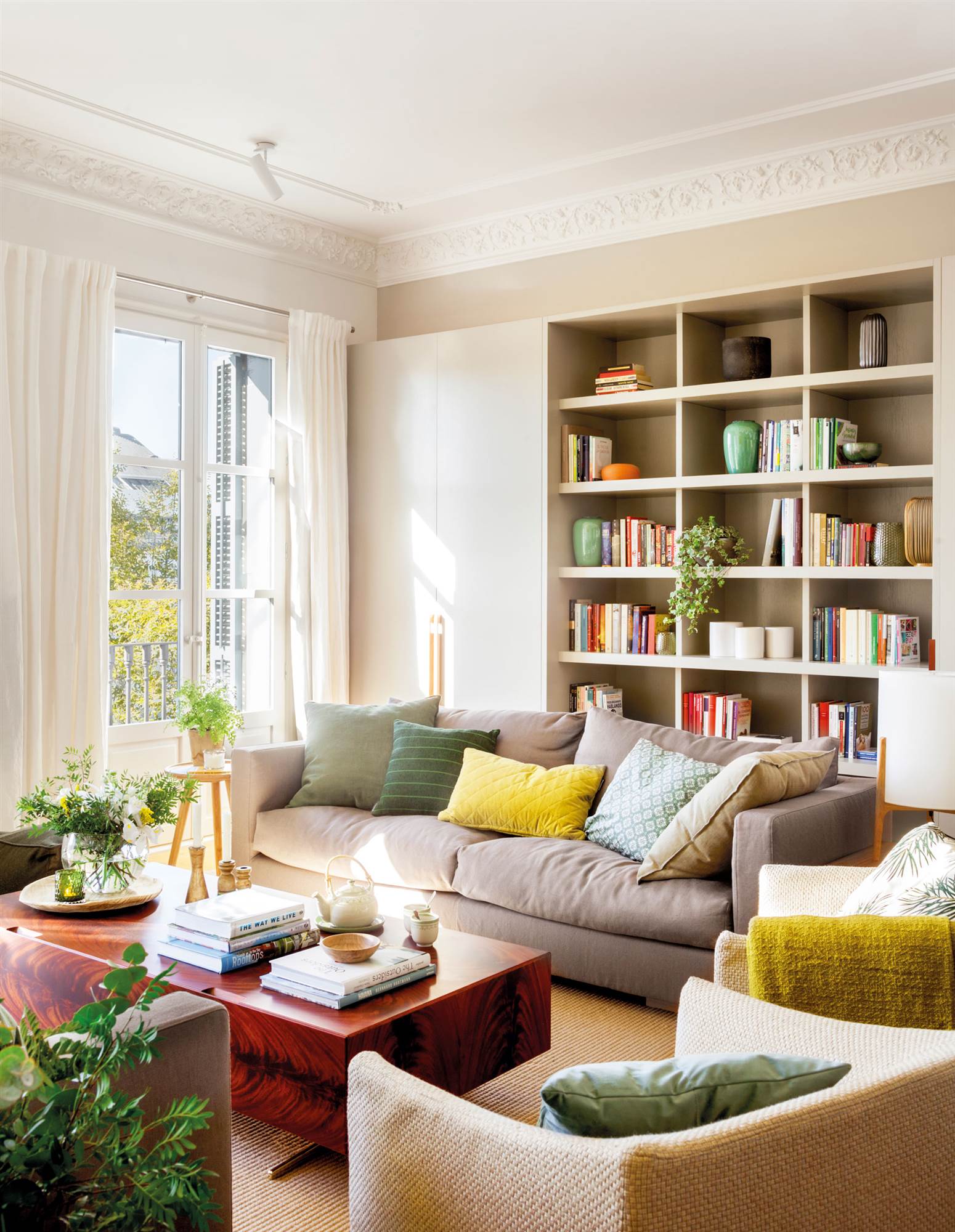 Un salón moderno con sofá gris y librería.