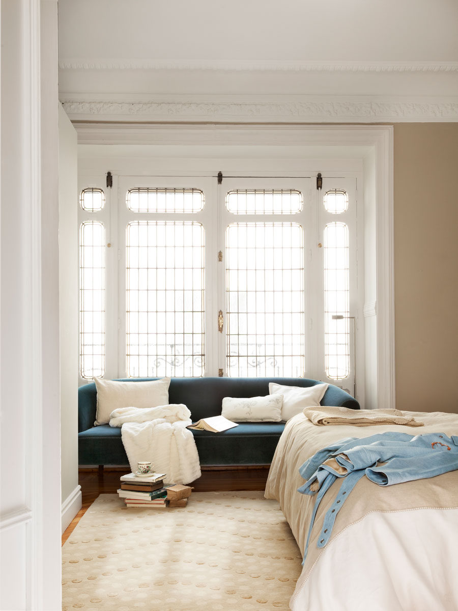 Dormitorio regio con molduras y ventana con sofá azul