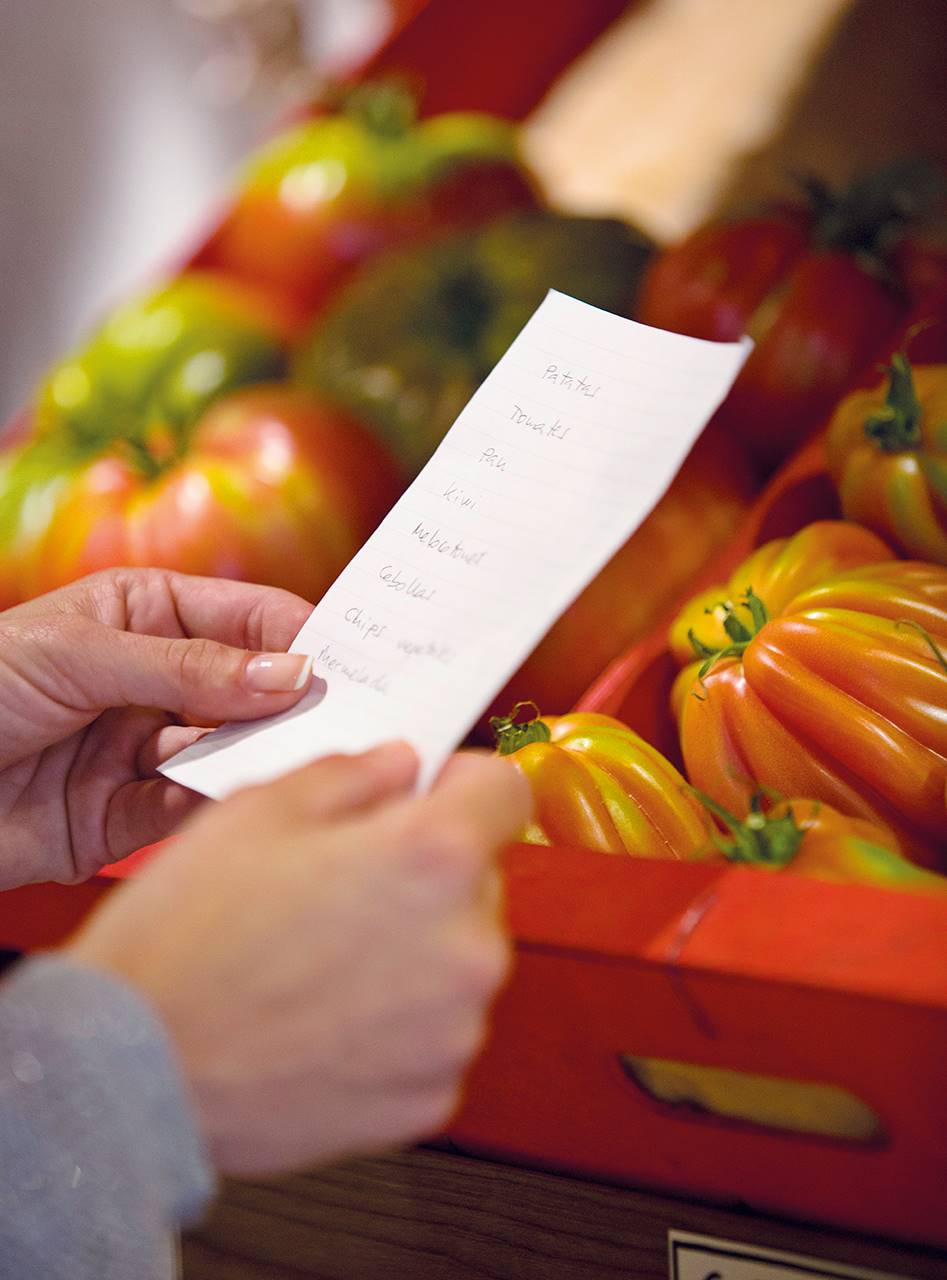 Lista de la compra con tomates de fondo.