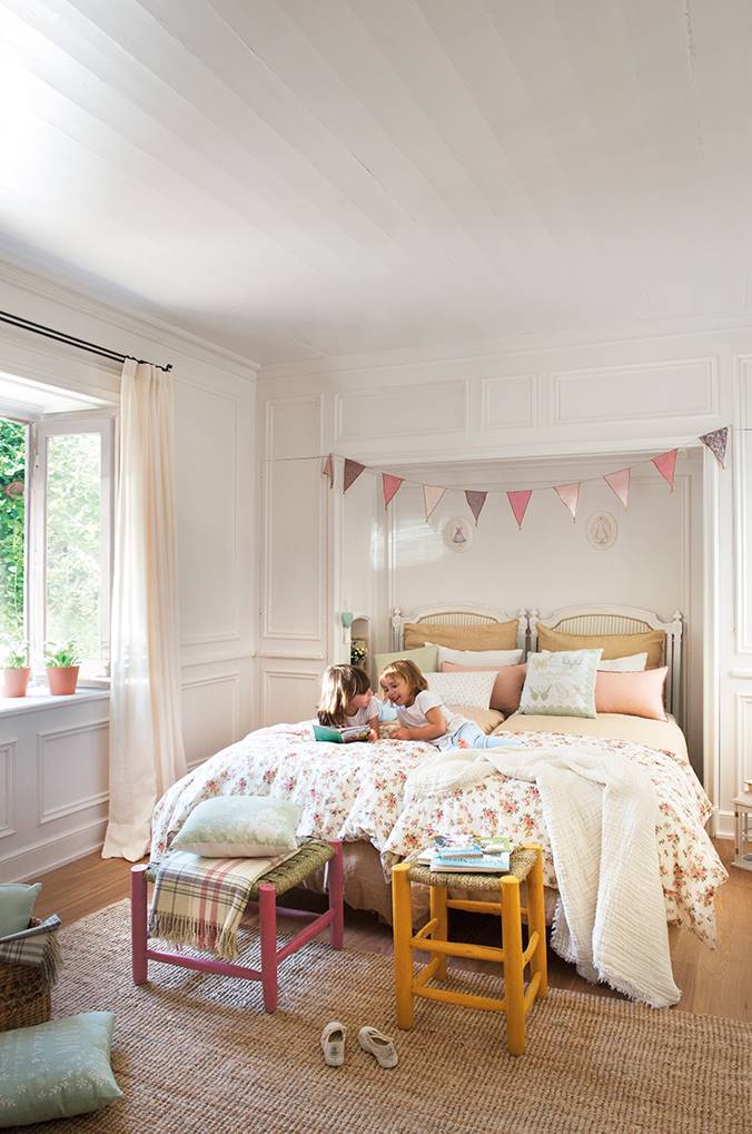 Habitación infantil con dos camas en una, dos taburetes, molduras y guirnalda en el techo.