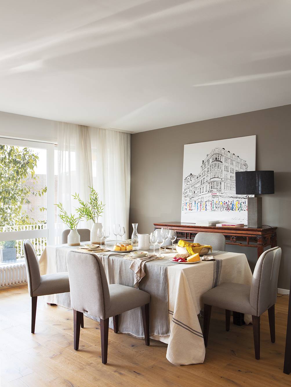 Comedor moderno con pared gris y sillas tapizadas.