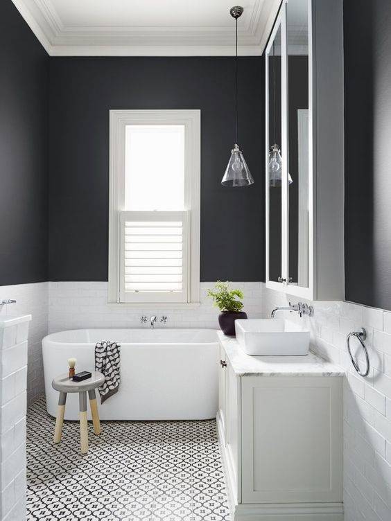Baño con arrimadero de azulejos blancos y paredes en negro.