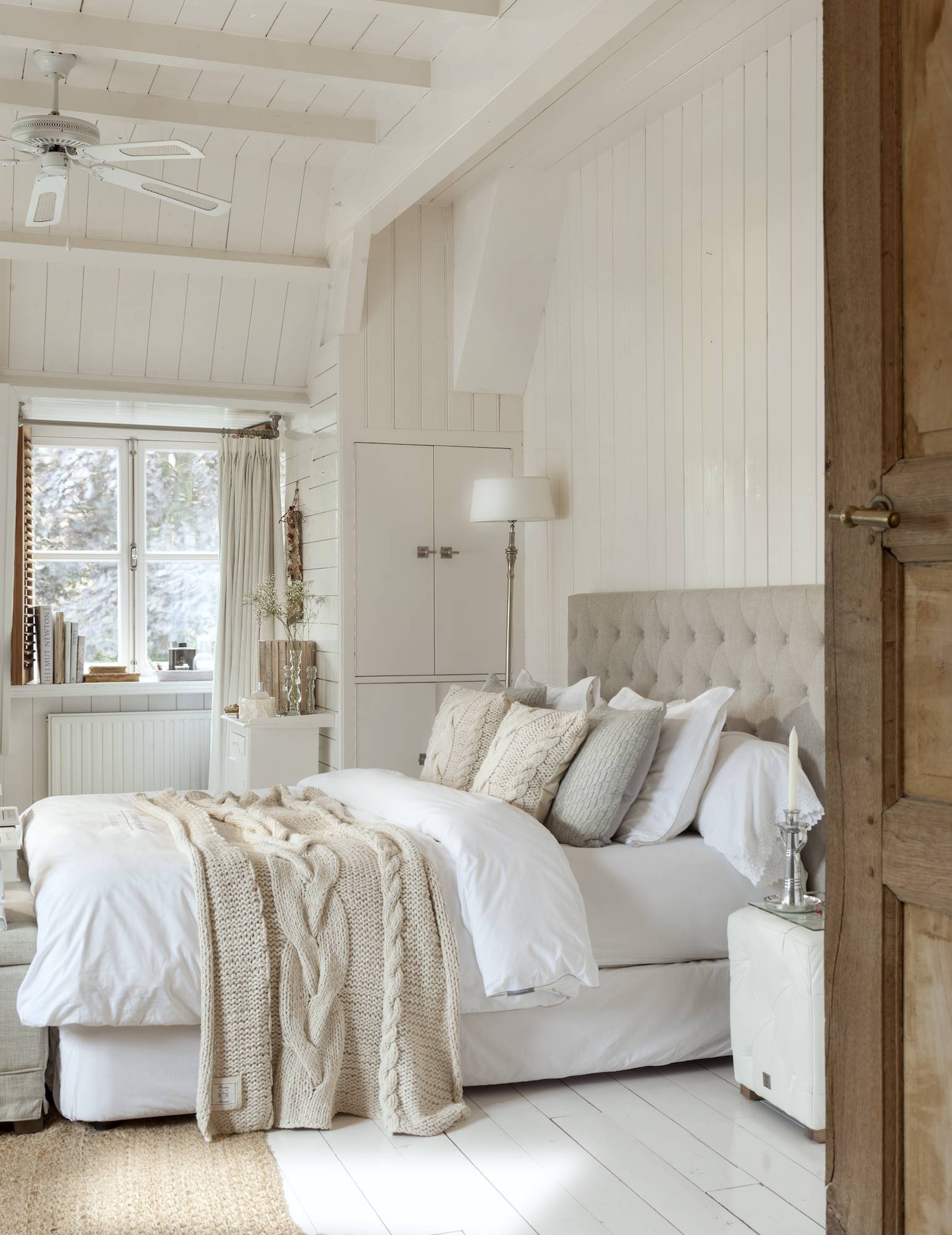 Dormitorio blanco con cabecero de color beige. 