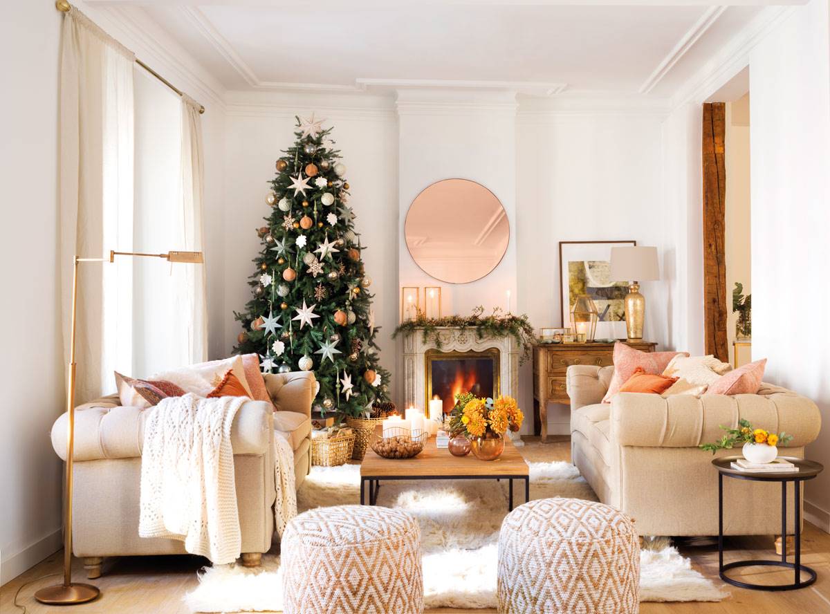 Salón clásico con sofás Chester, chimenea, pufs y árbol de Navidad alto con adornos. 