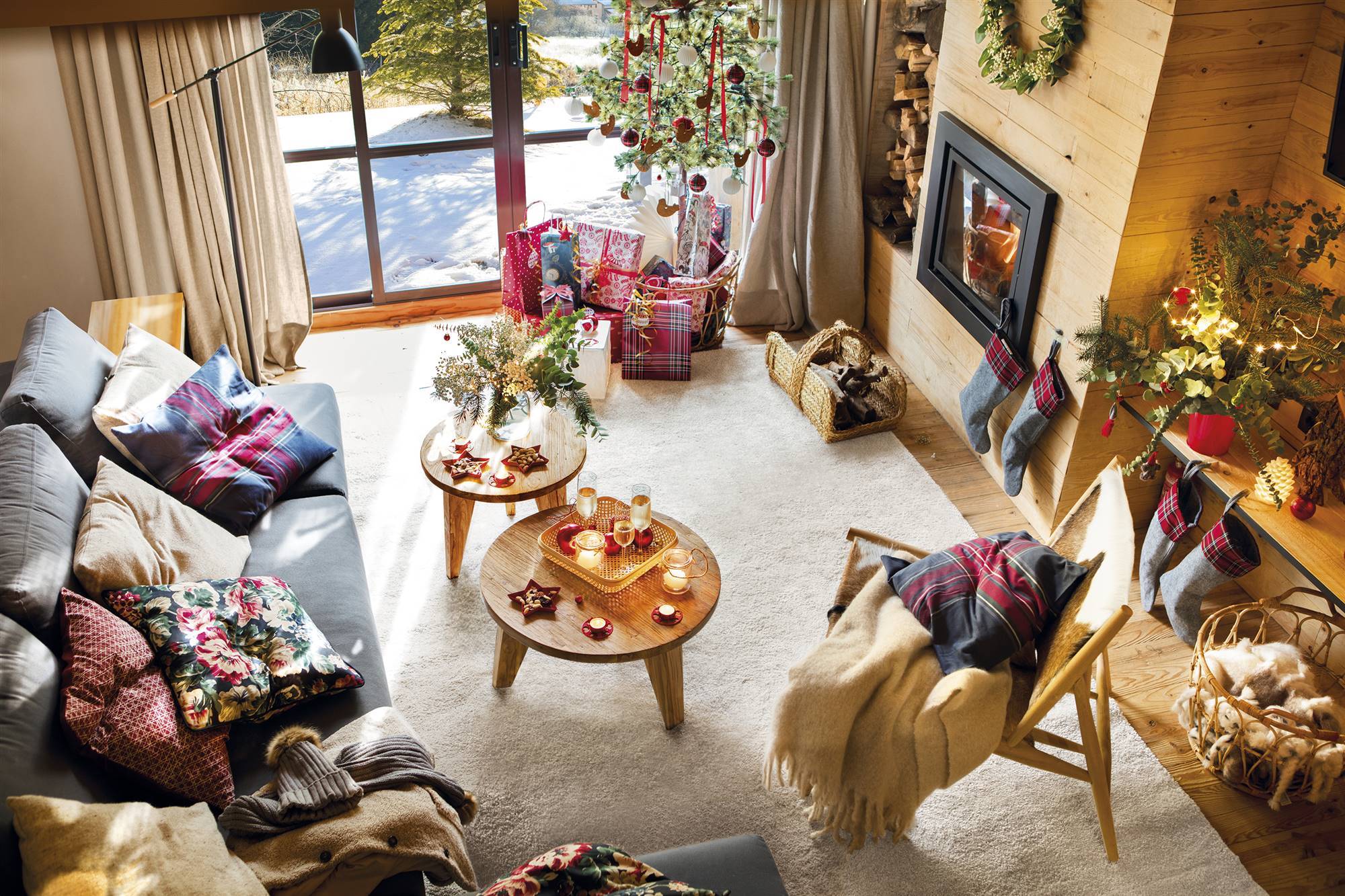 Salón rústico con chimenea de madera y sofá gris decorado por Navidad. 