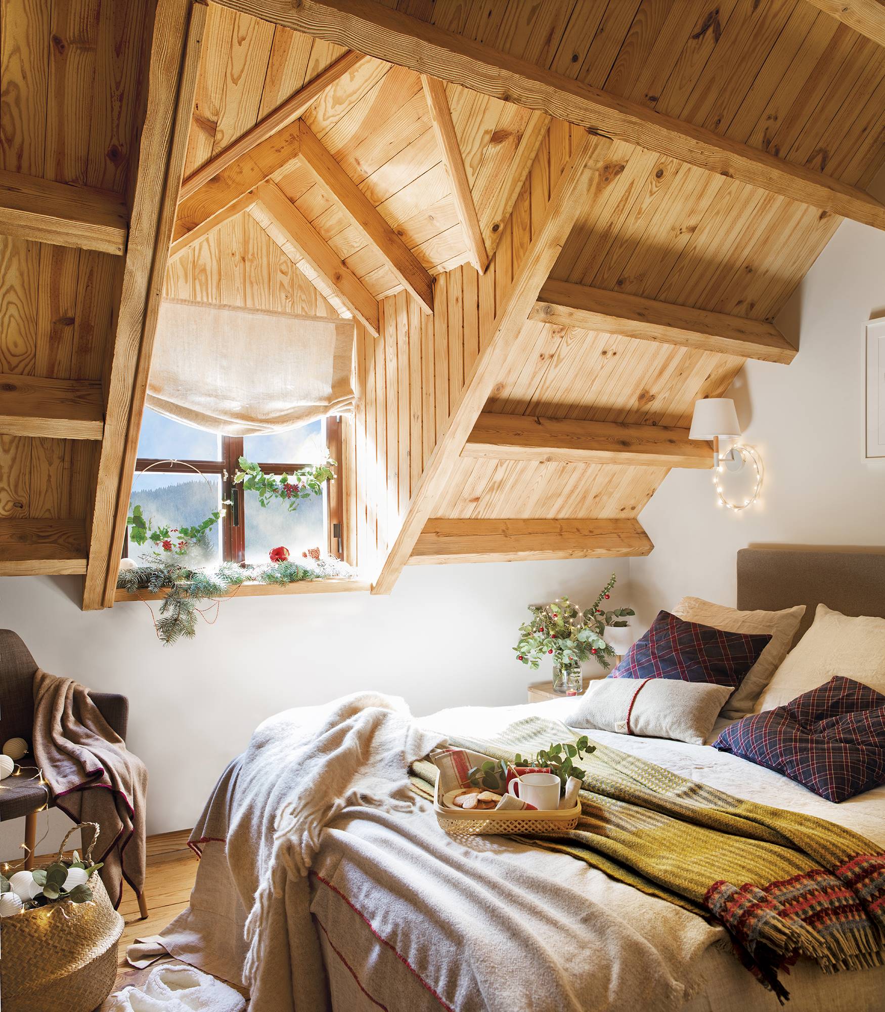 Dormitori abuhardillado con techos de madera y vigas decorado por Navidad. 